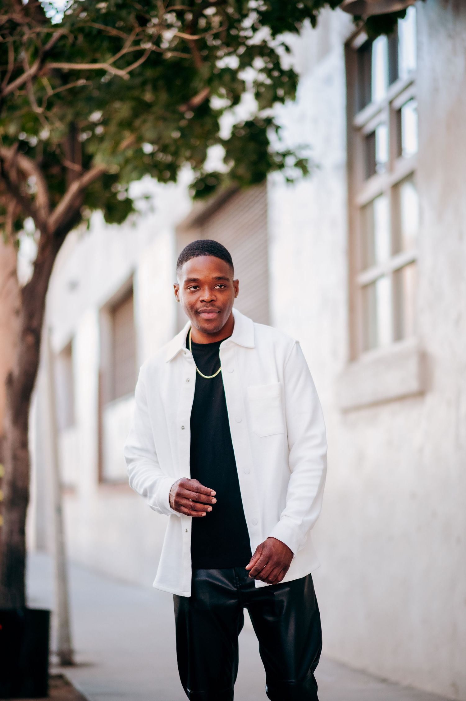 Professional photos showing person in white blazer and black shirt against light wall backdrop.