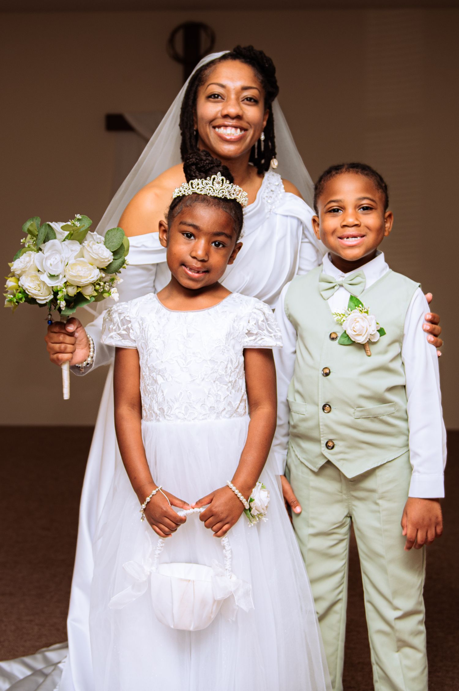 Children in white formal attire and light colored suits pose together at a wedding celebration.