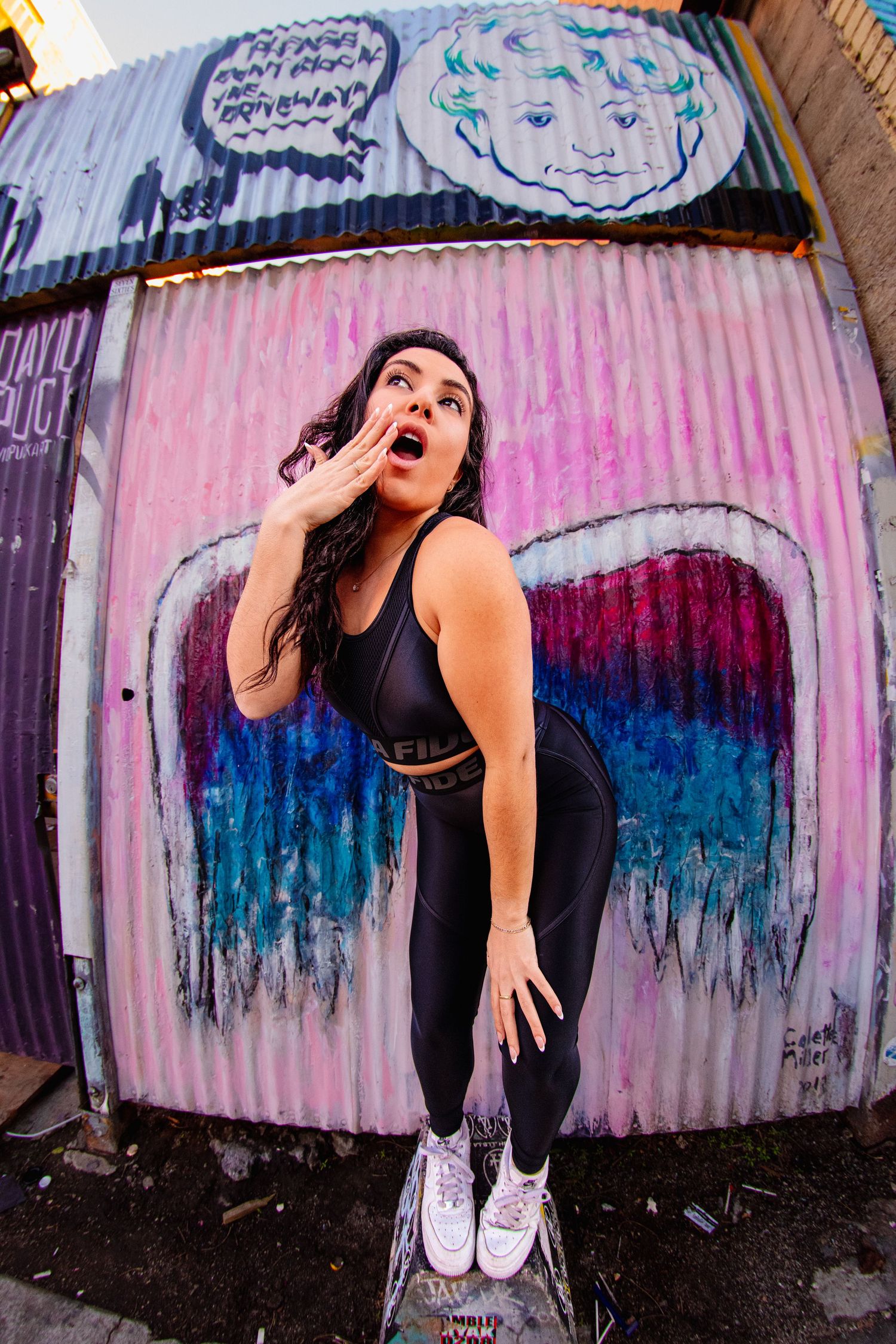 Dynamic dance poses photographed against vibrant graffiti wall featuring blue and pink urban art elements.