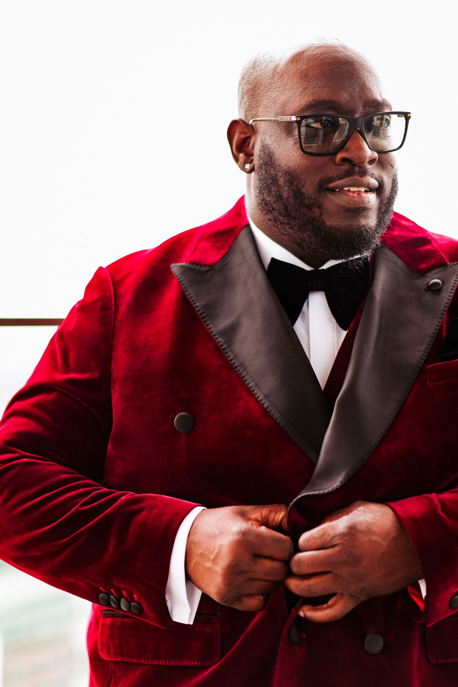 A person wearing a red velvet blazer and black bowtie poses in a sequence of celebratory expressions.