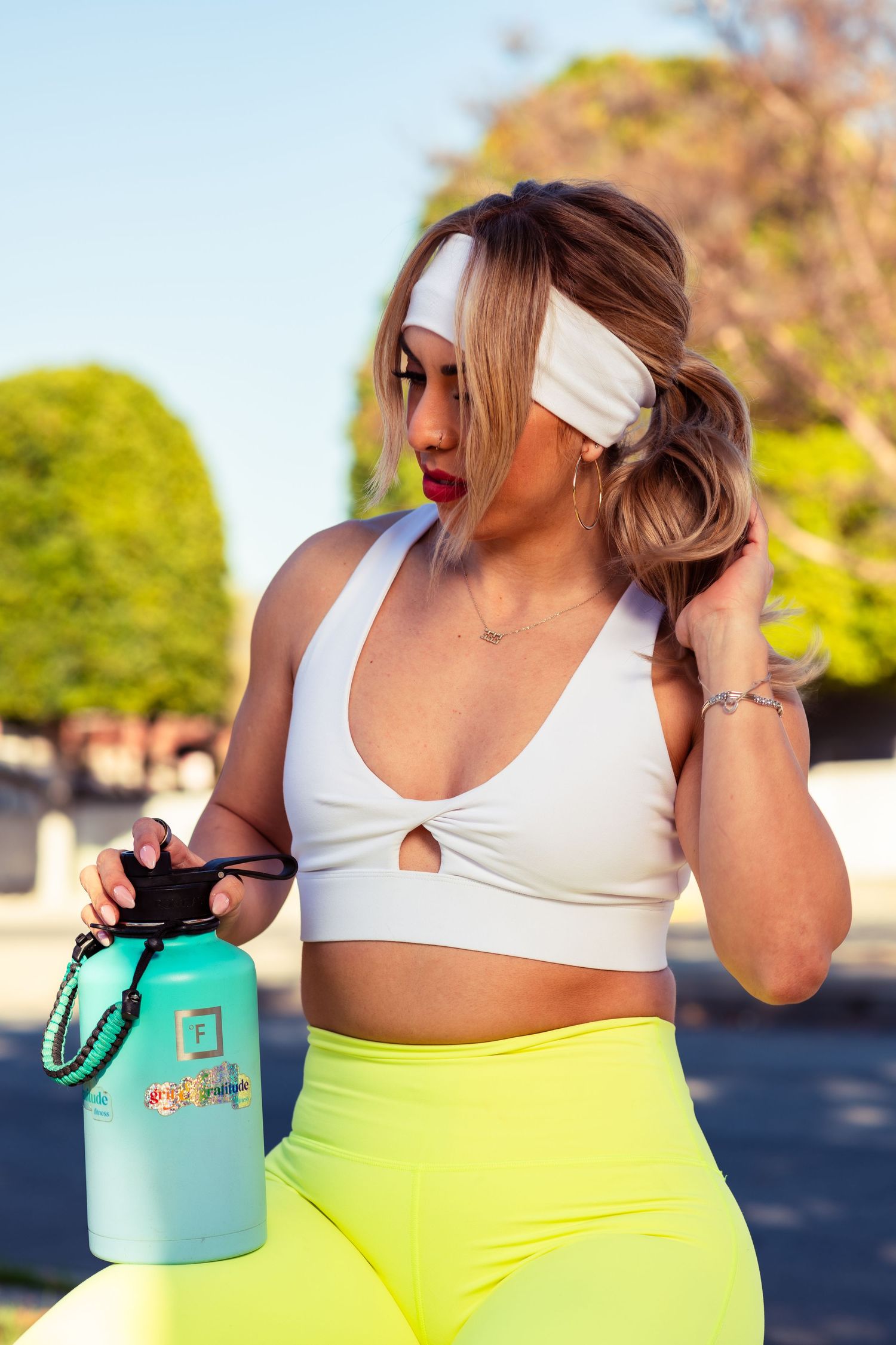 Fitness photo showing neon yellow leggings and white sports bra with turquoise water bottle.