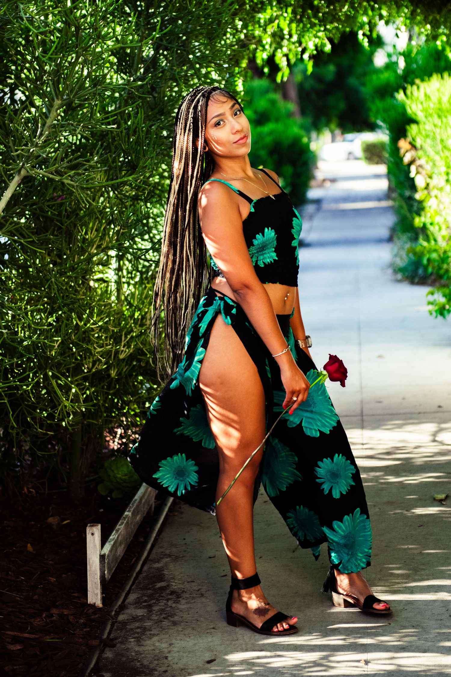 A person in a teal dress poses in a series of artistic shots along a sunlit garden pathway.