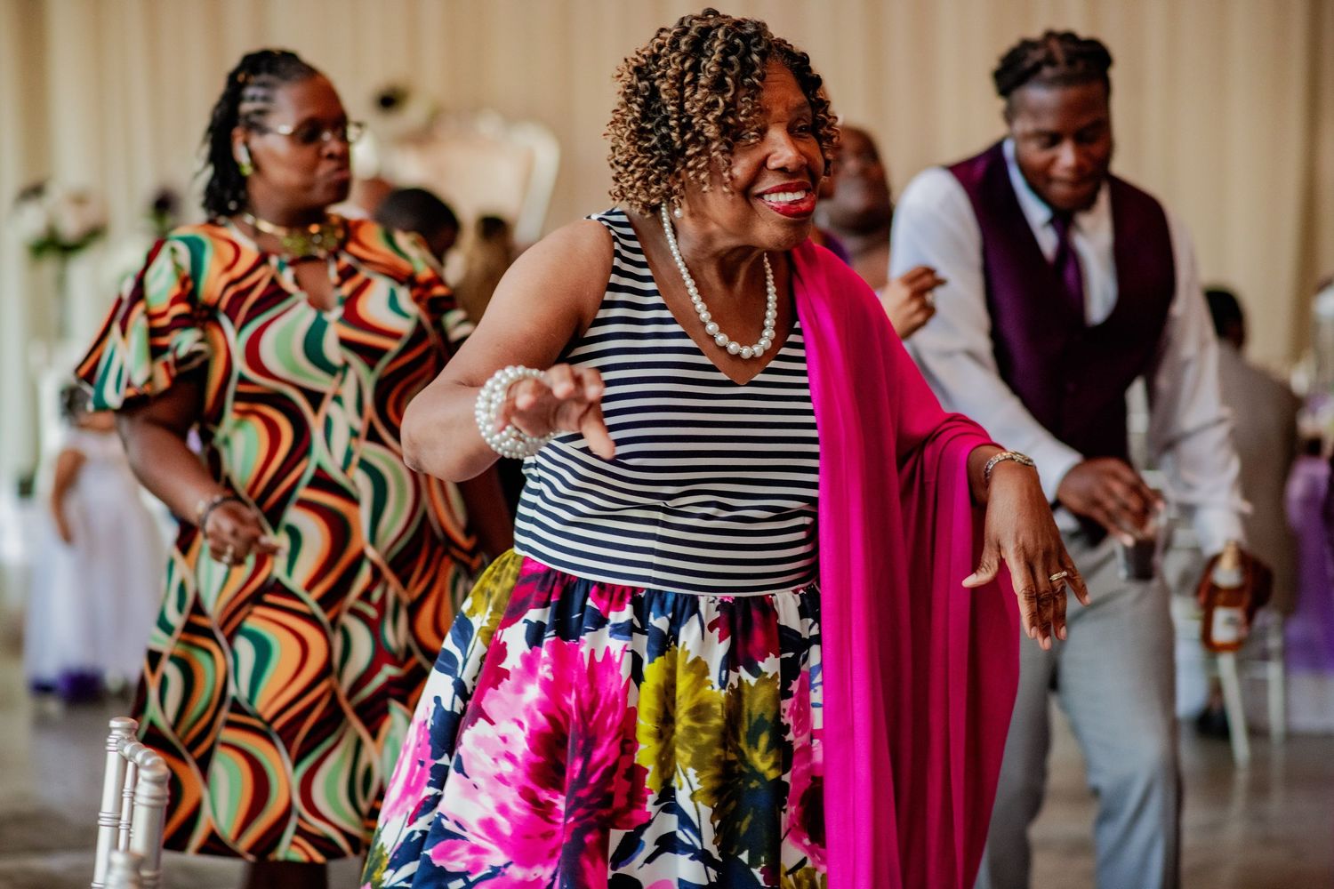 Guests dancing and celebrating together at a lively wedding reception with colorful outfits and decor.