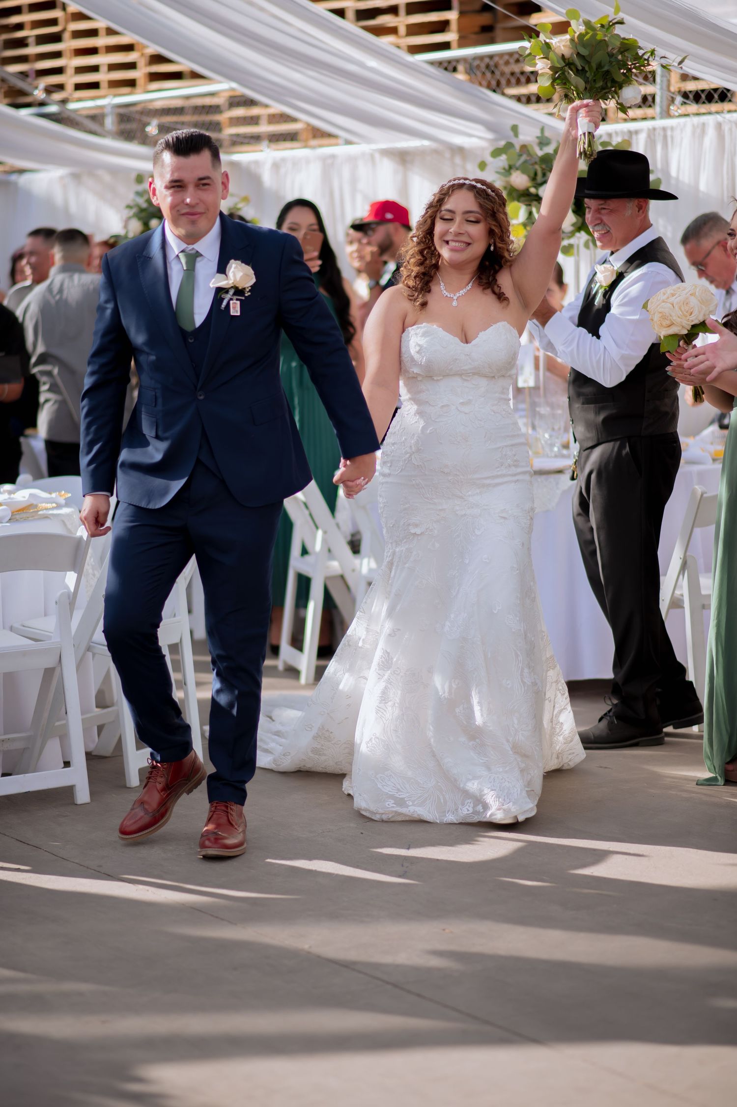 Wedding guests dancing and celebrating on a covered outdoor dance floor.