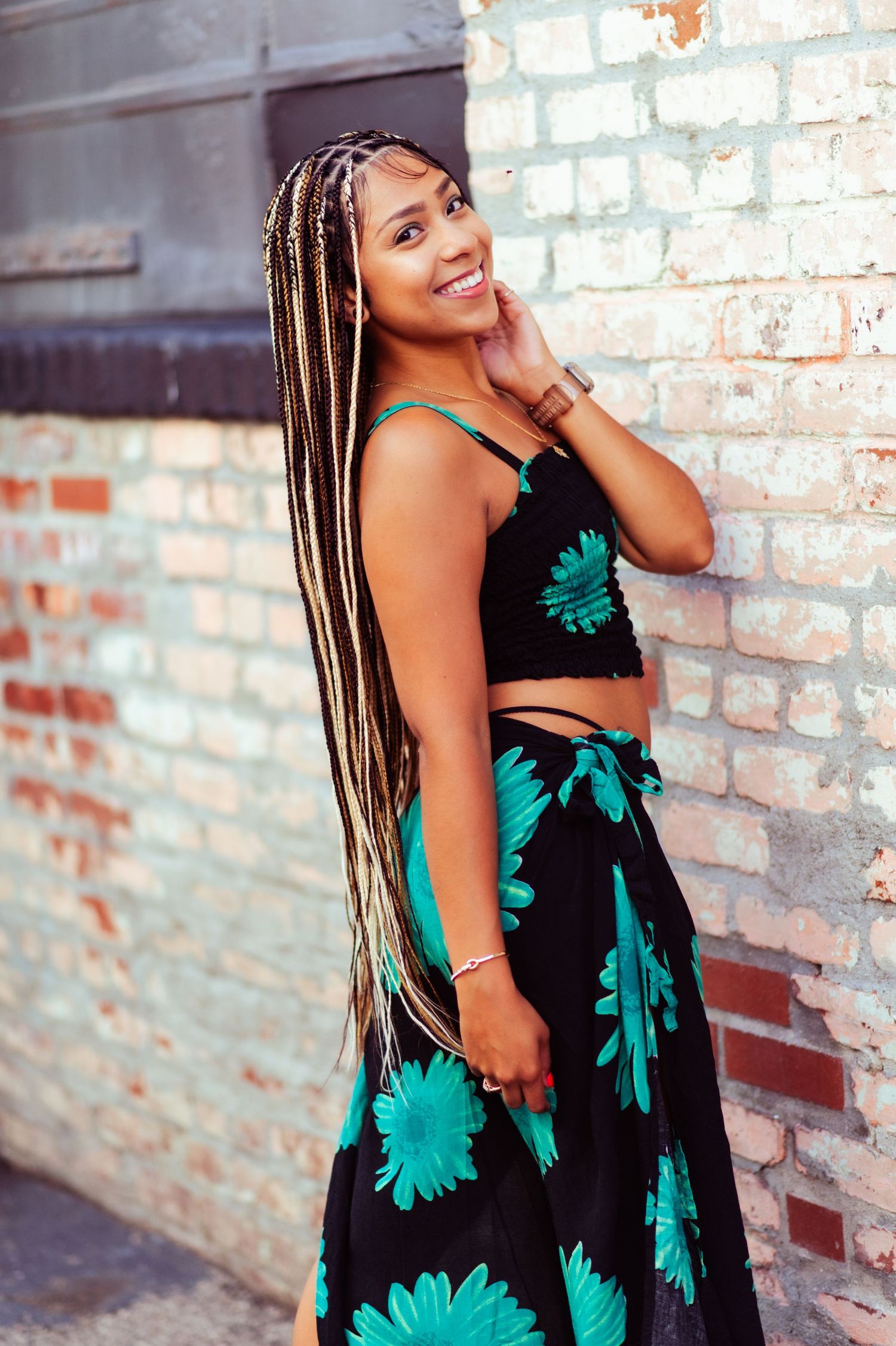 Summer style photo series showcasing a floral dress against an urban brick wall backdrop.