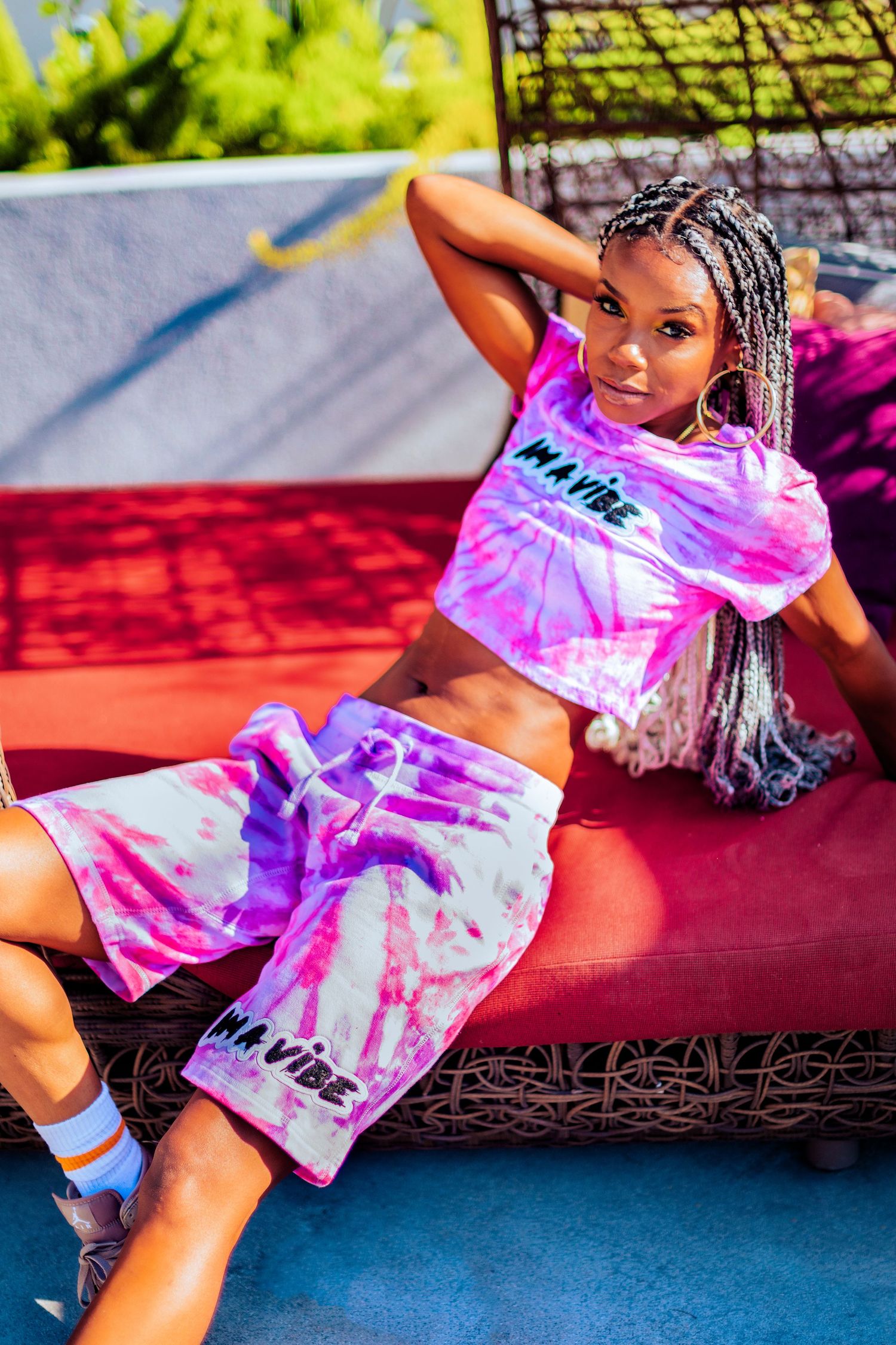 Person in tie-dye pink and white t-shirt strikes dynamic poses against vibrant outdoor backdrop.