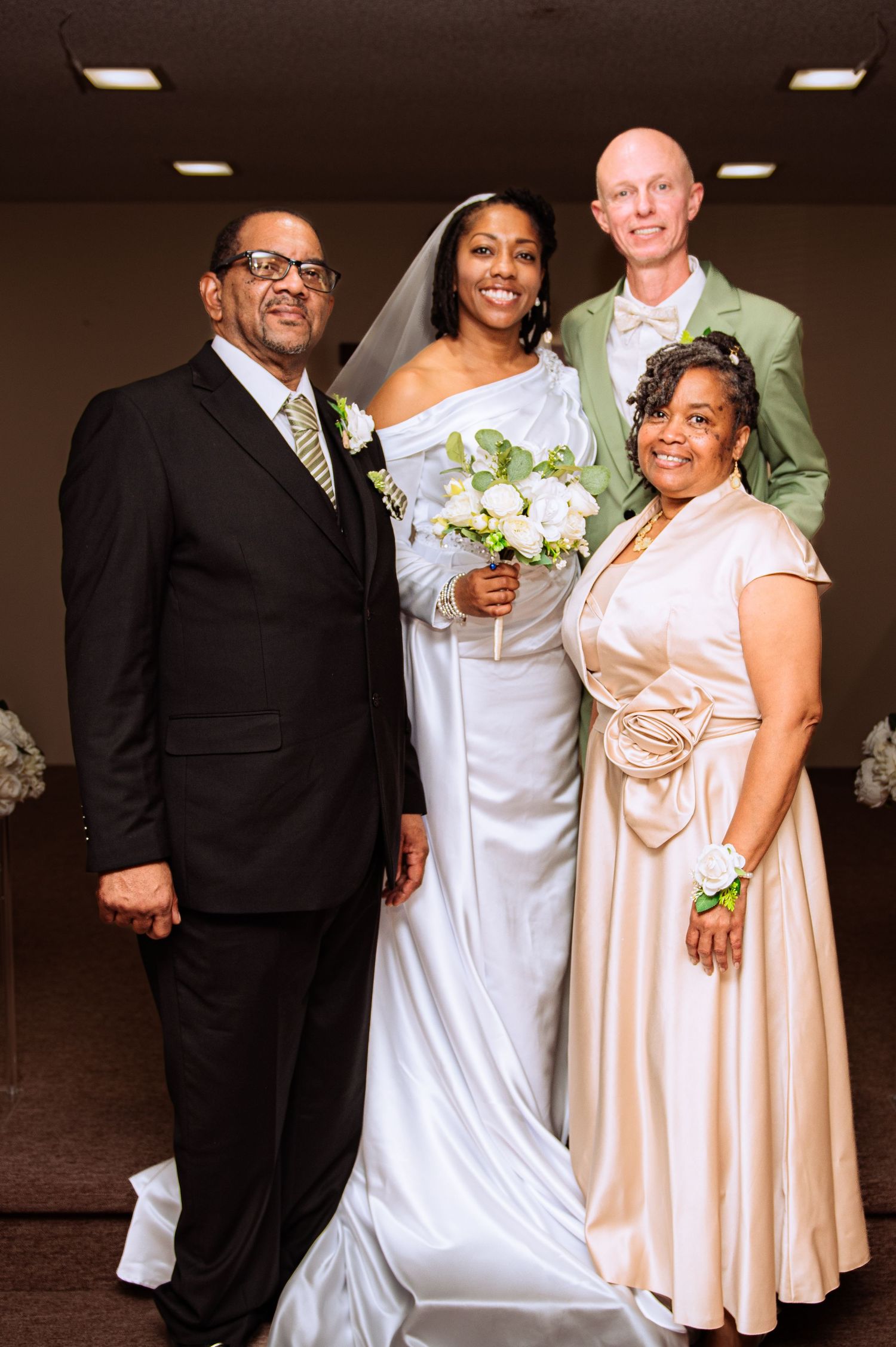 Wedding party poses together in formal attire with the bride in white and bridesmaids in peach-colored dresses.