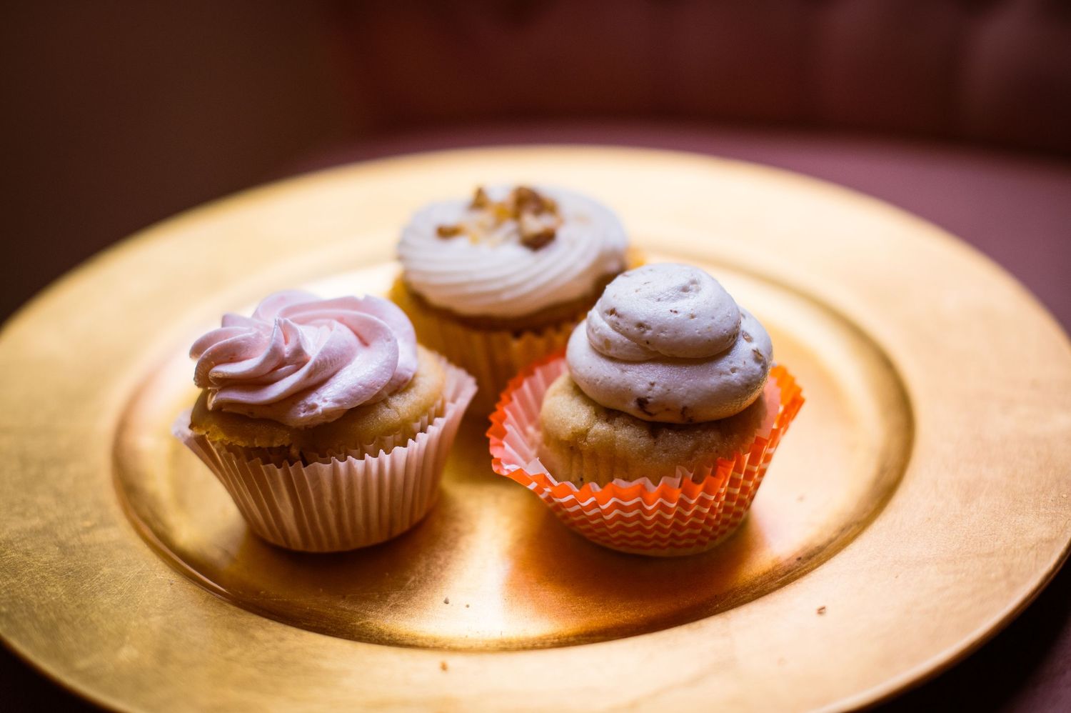 Chocolate cupcakes with frosting and strawberry garnish displayed on wooden plates under warm lighting.