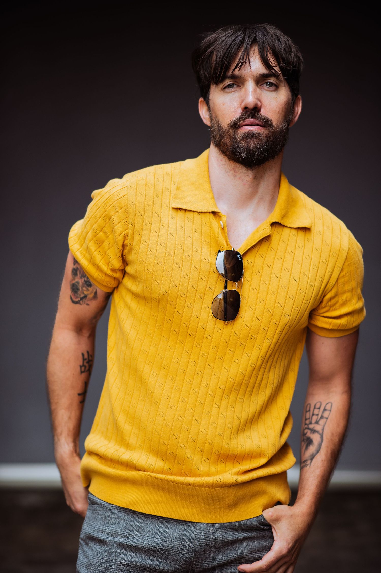 A stylish yellow polo shirt is featured in a dark studio portrait setting.