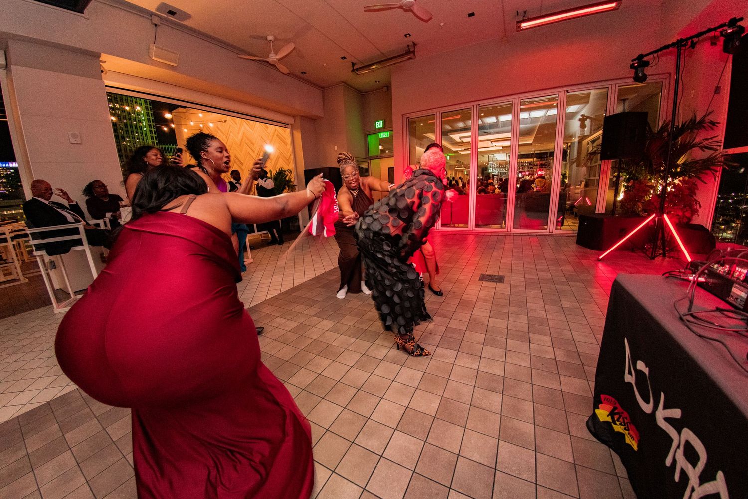 Reception venue with red ambient lighting and tiled floor where wedding guests celebrate.