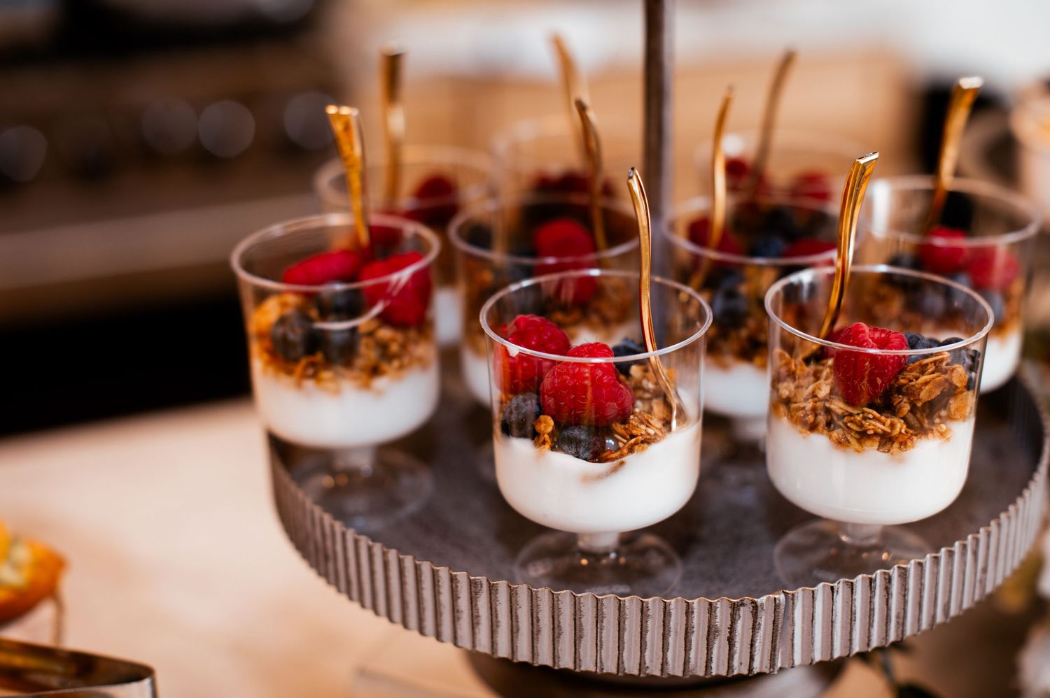 Elegant dessert display featuring parfait glasses with layered treats and fresh berries.