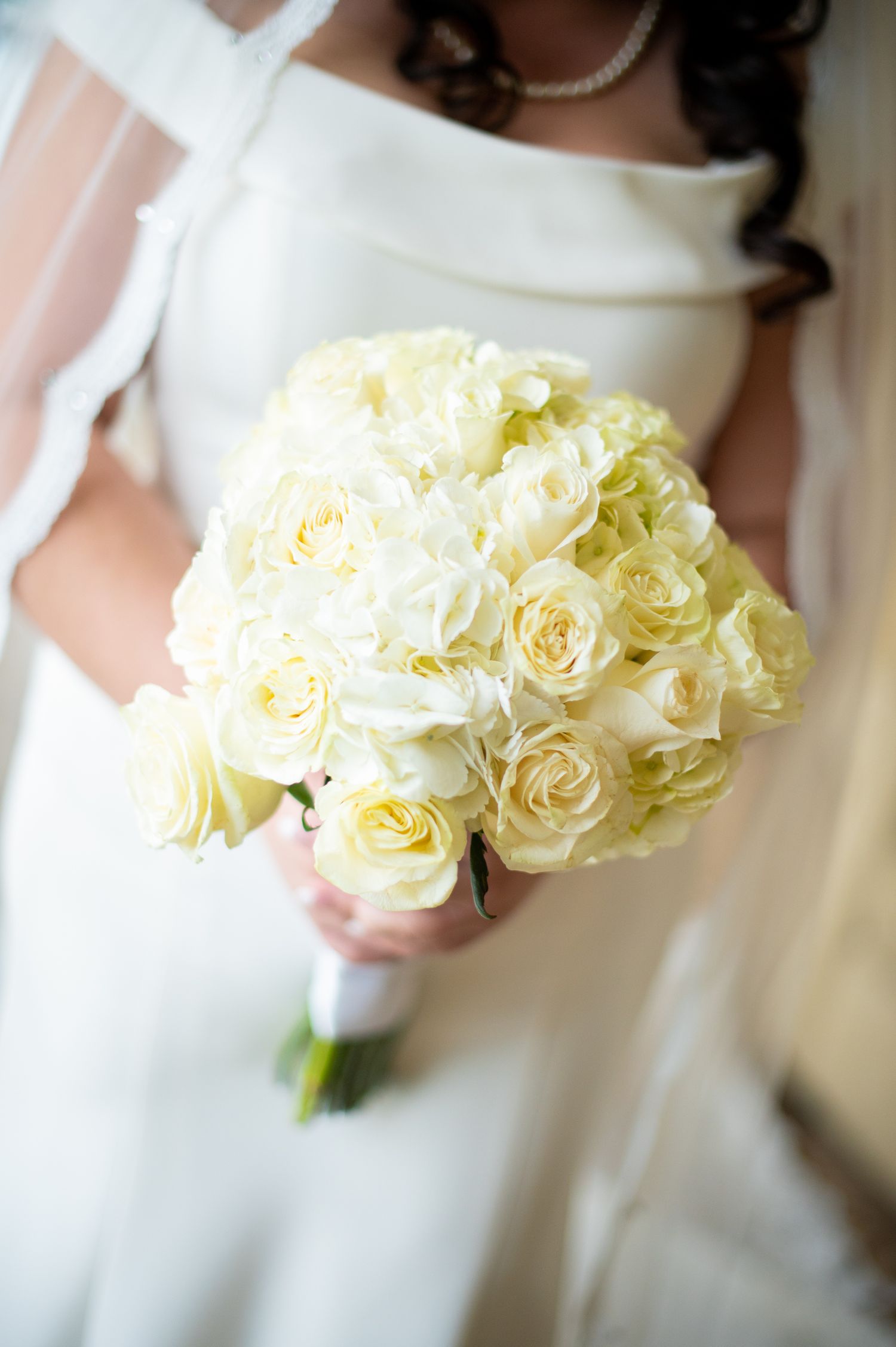 A delicate bouquet of cream colored roses in soft focus creates an elegant wedding detail.