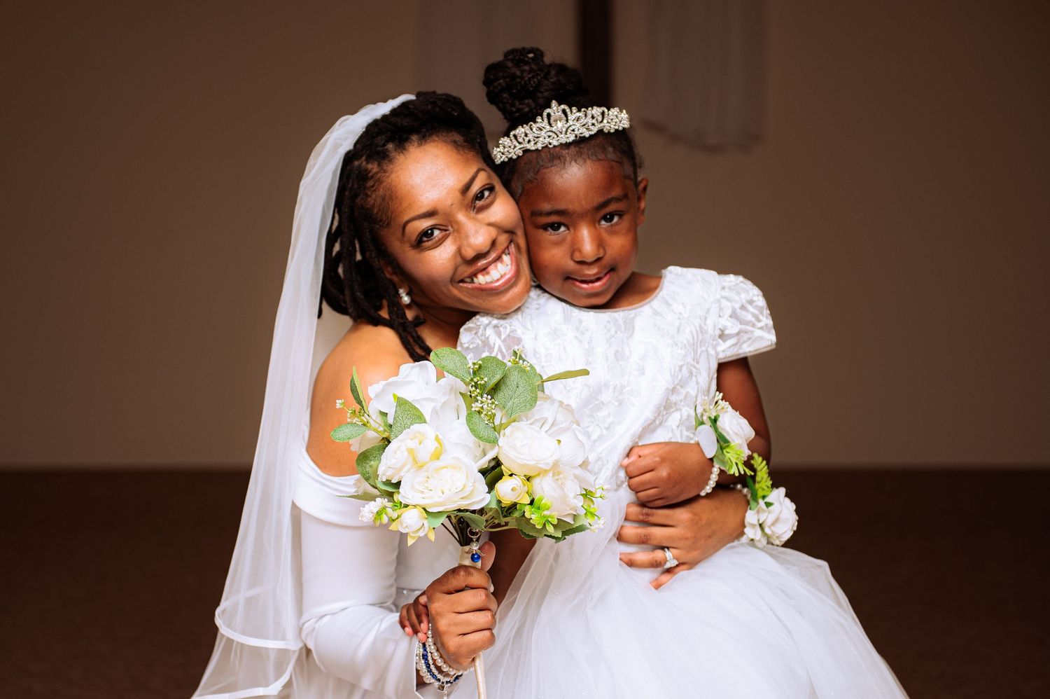A wedding couple shares tender moments while holding white floral bouquets.