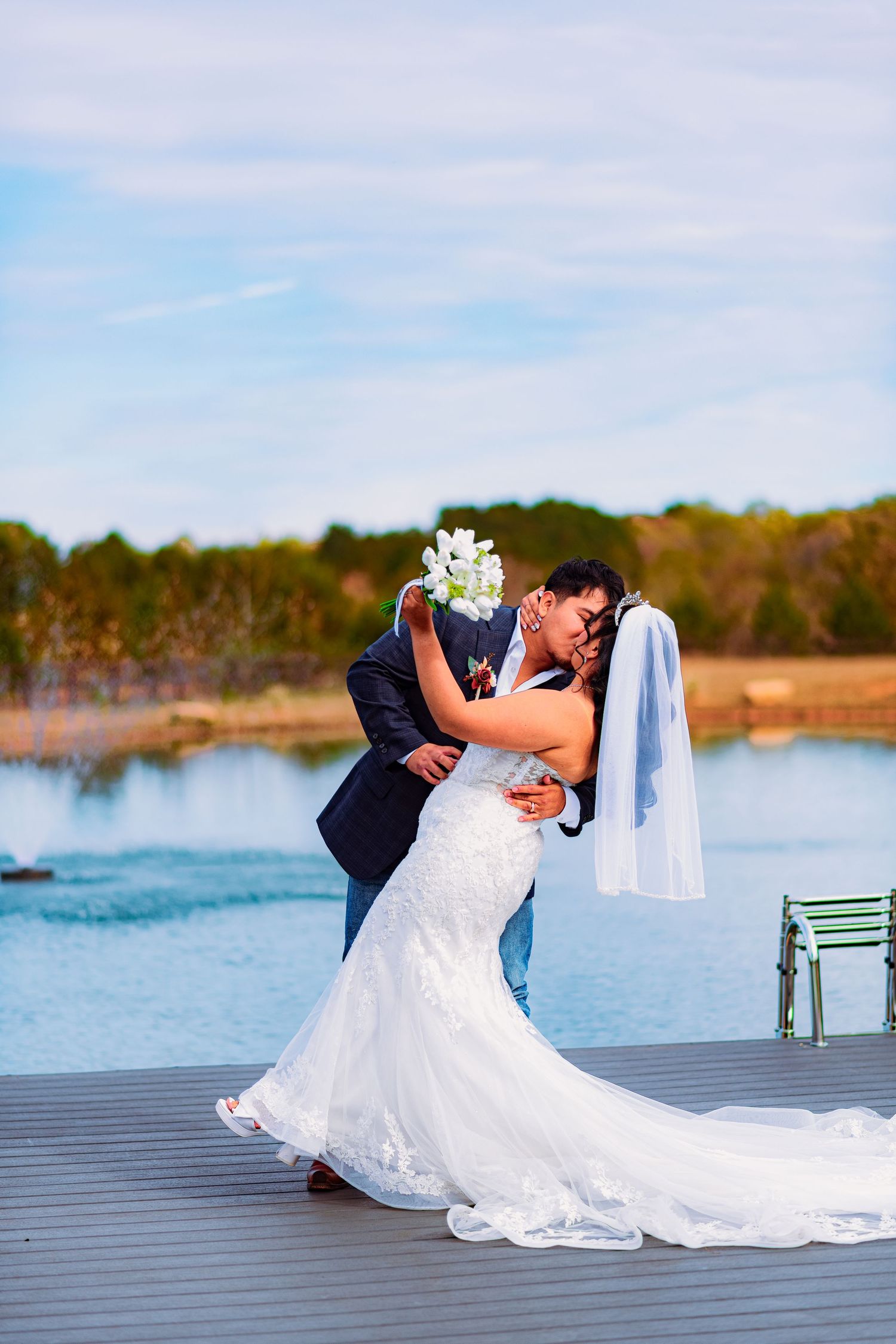 Romantic wedding couple shares intimate moments on a wooden dock by a serene lake.