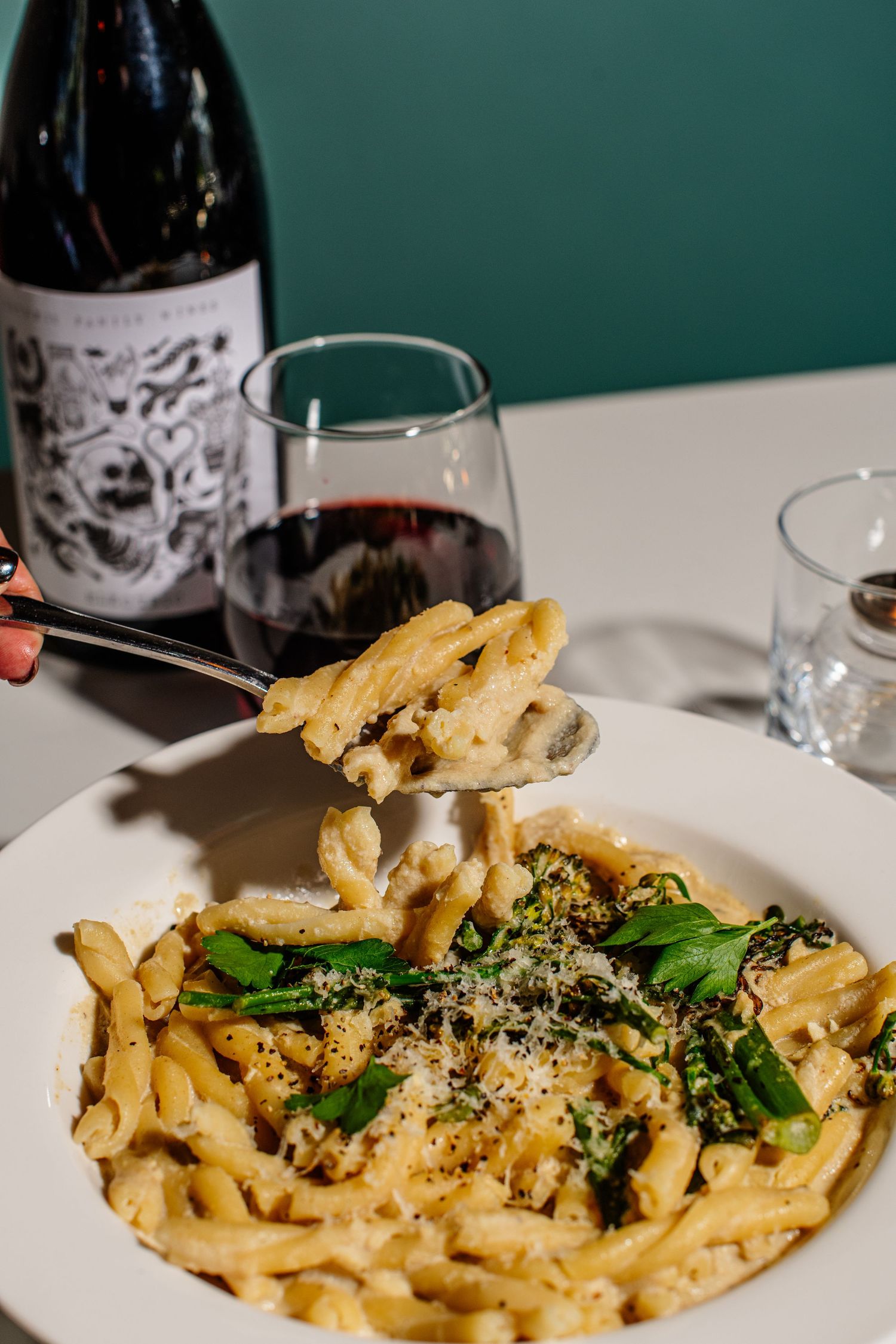 Creamy mac and cheese pasta topped with fresh herbs and grated parmesan cheese on a white plate.