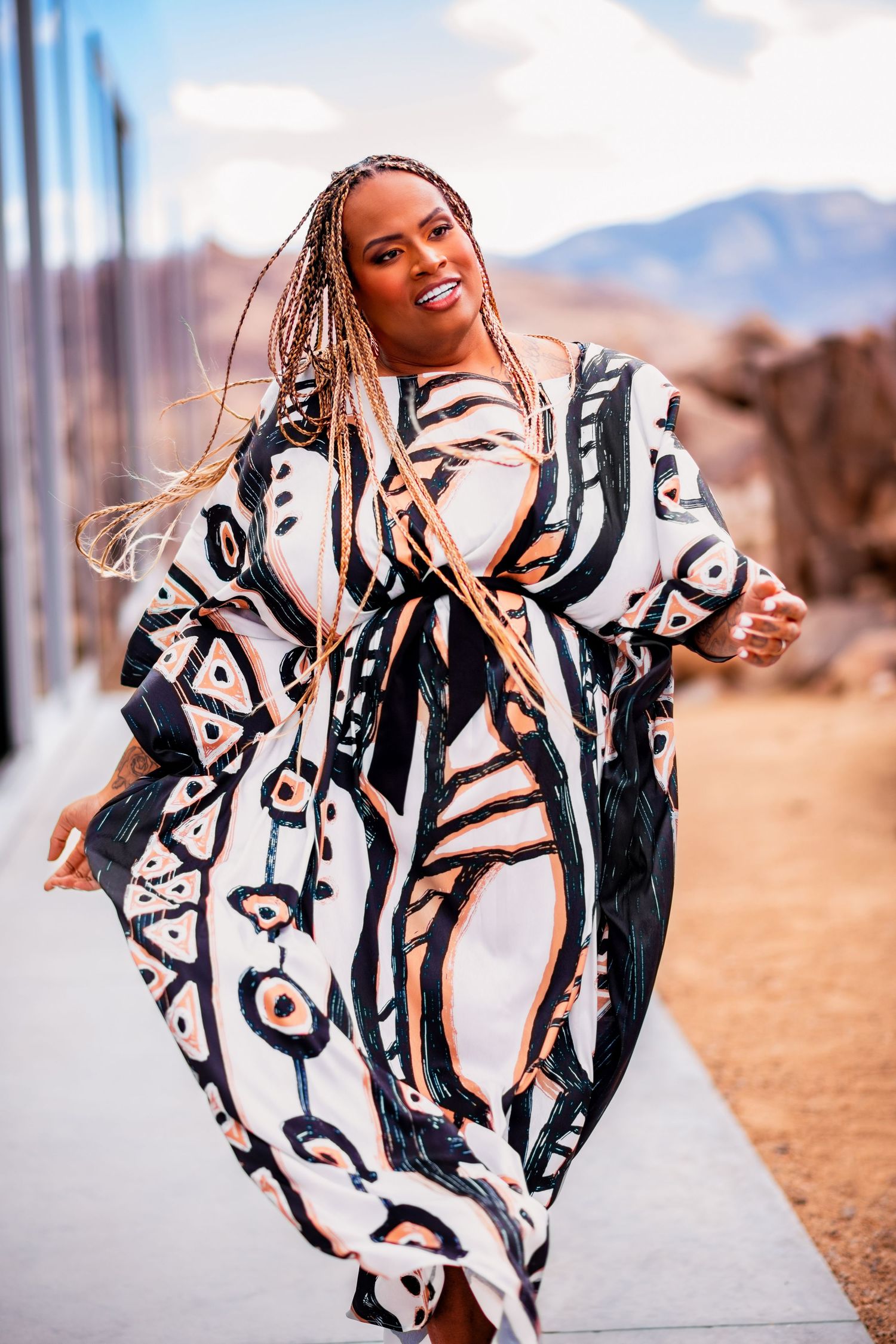 Fashion model in bold black and white printed dress poses dramatically outdoors.