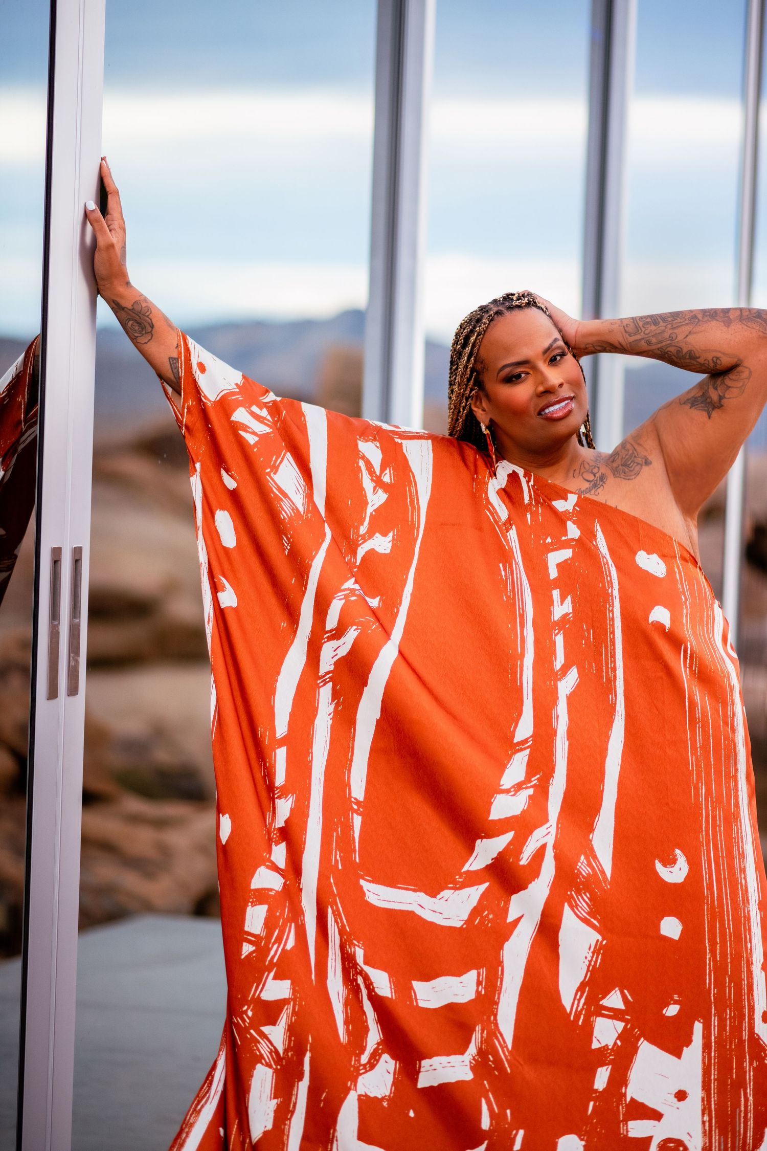 Vibrant orange kaftan with white abstract pattern photographed in desert setting.