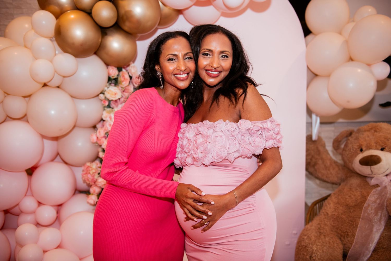 A celebratory moment captured against a pink and gold balloon backdrop.