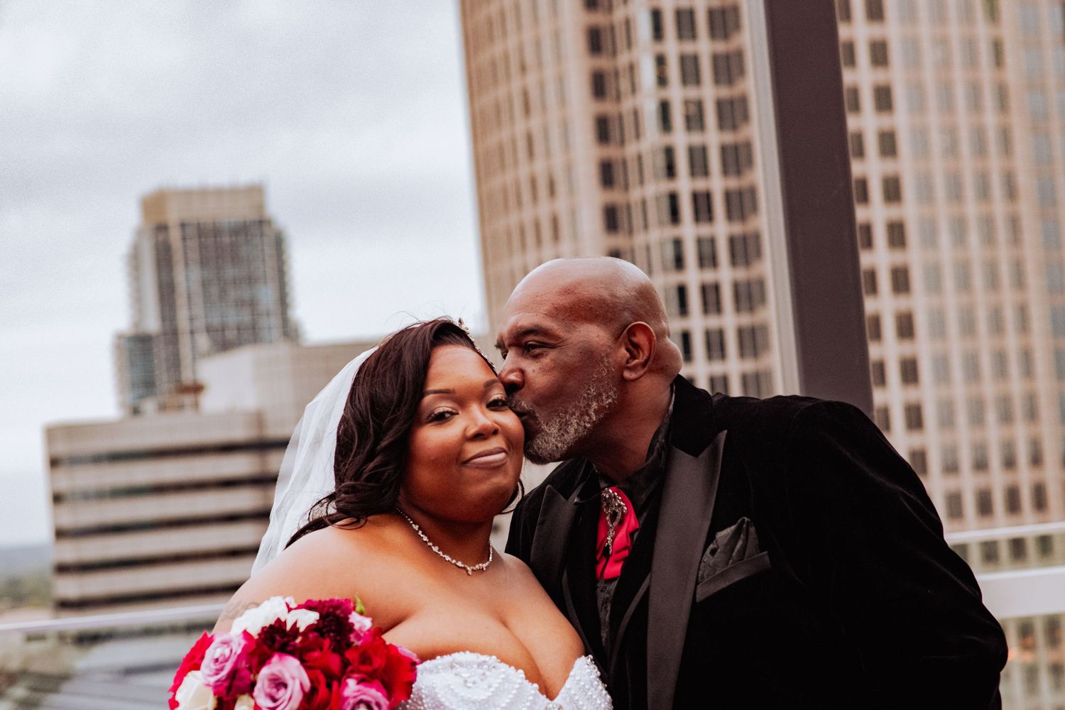 Romantic wedding portraits captured against a cityscape with modern buildings in the background.