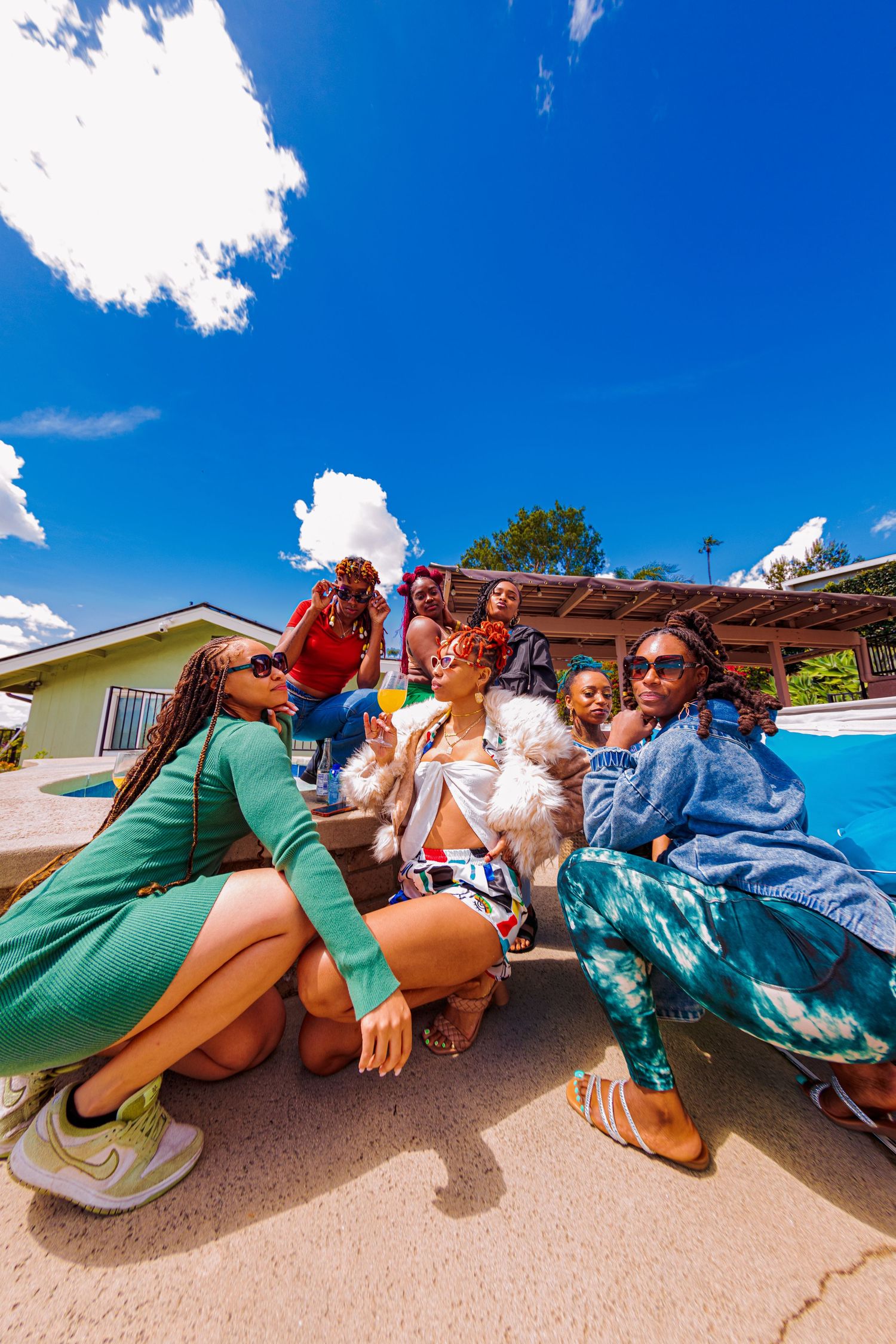 Group of baddies in the hills of Whittier, California lying in playful poses on ground for fun wide-angle photo under bright blue sky.
