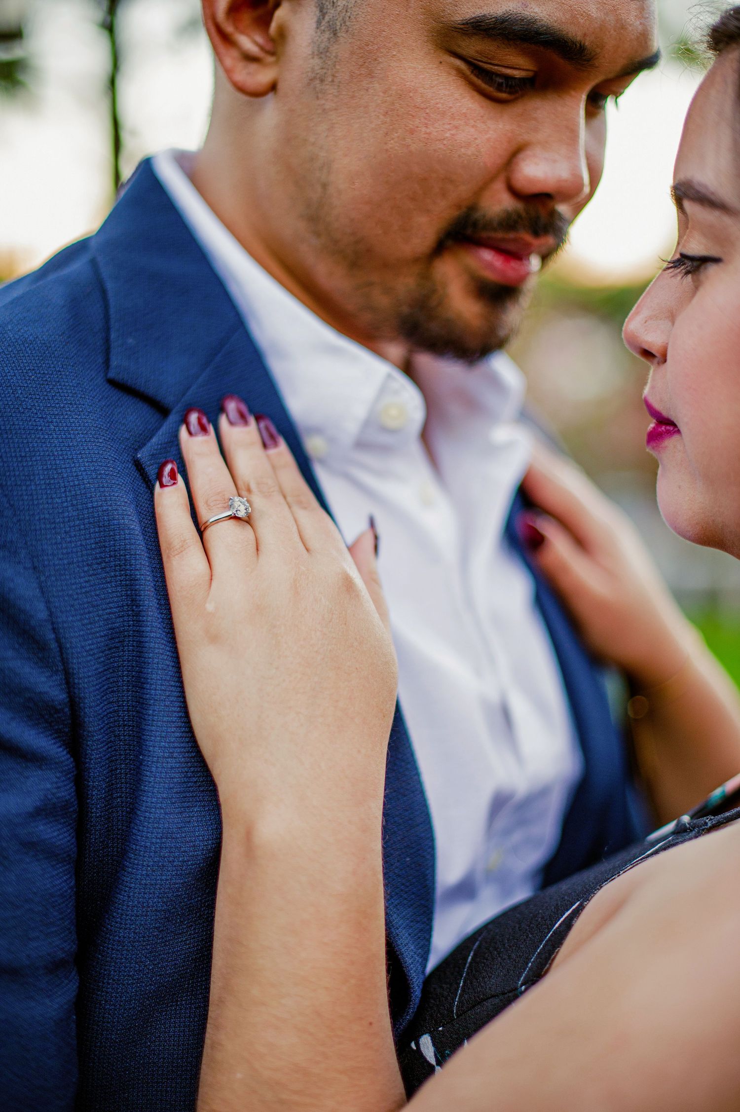 Close-up sequence showing couple's intimate moment with red nail polish and engagement ring details in navy and white attire.