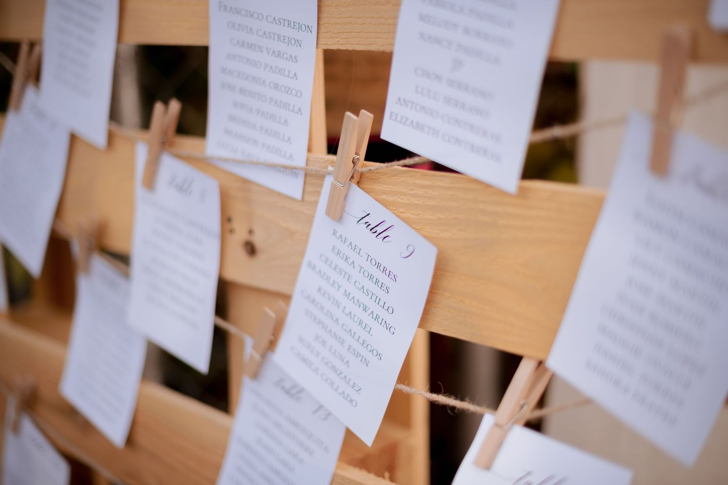 Close-up of paper notes arranged on wooden slats creating a seating chart display.