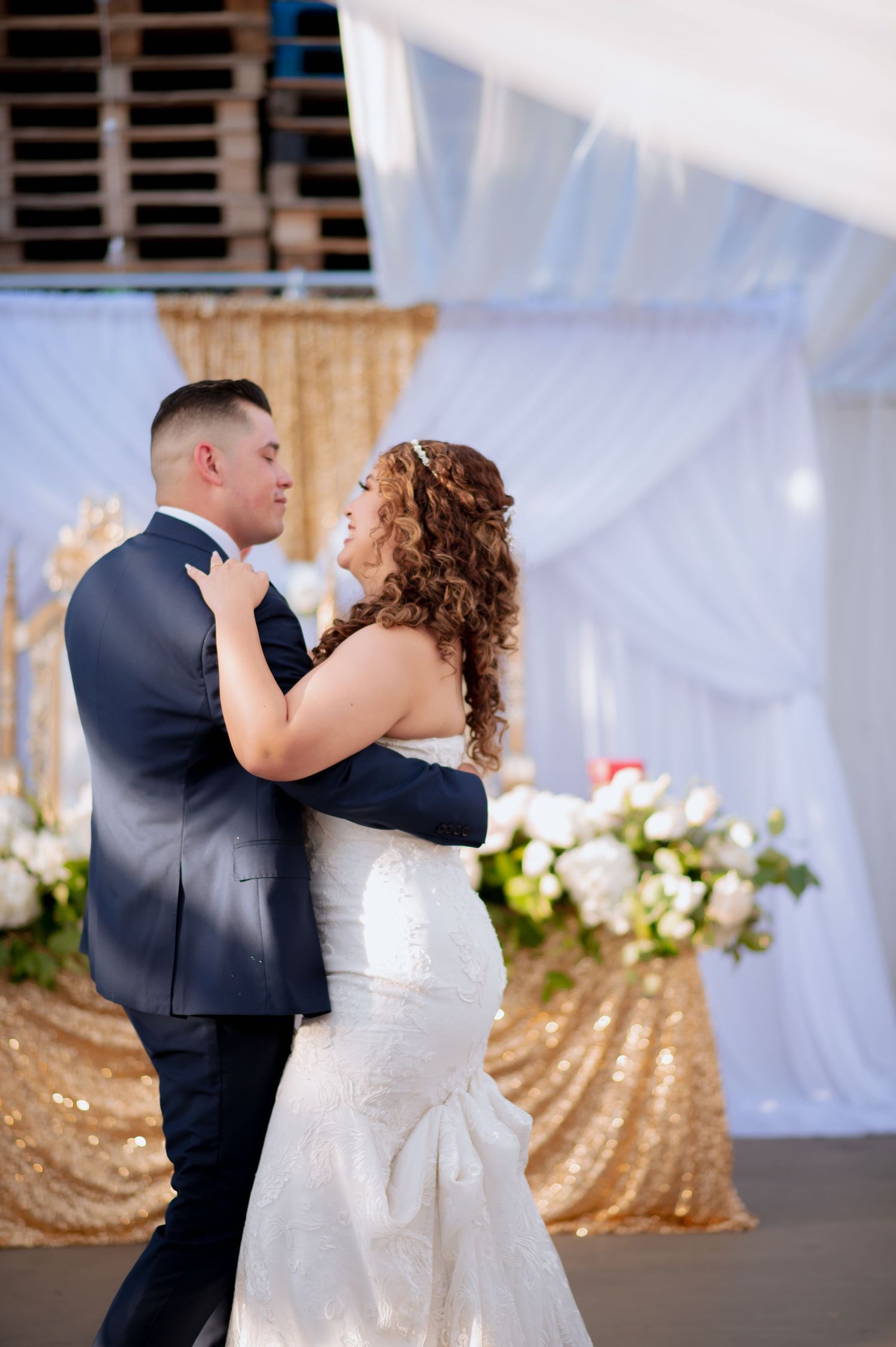 Elegant dance moves captured at a wedding reception with white drapery and gold sequin decorations.