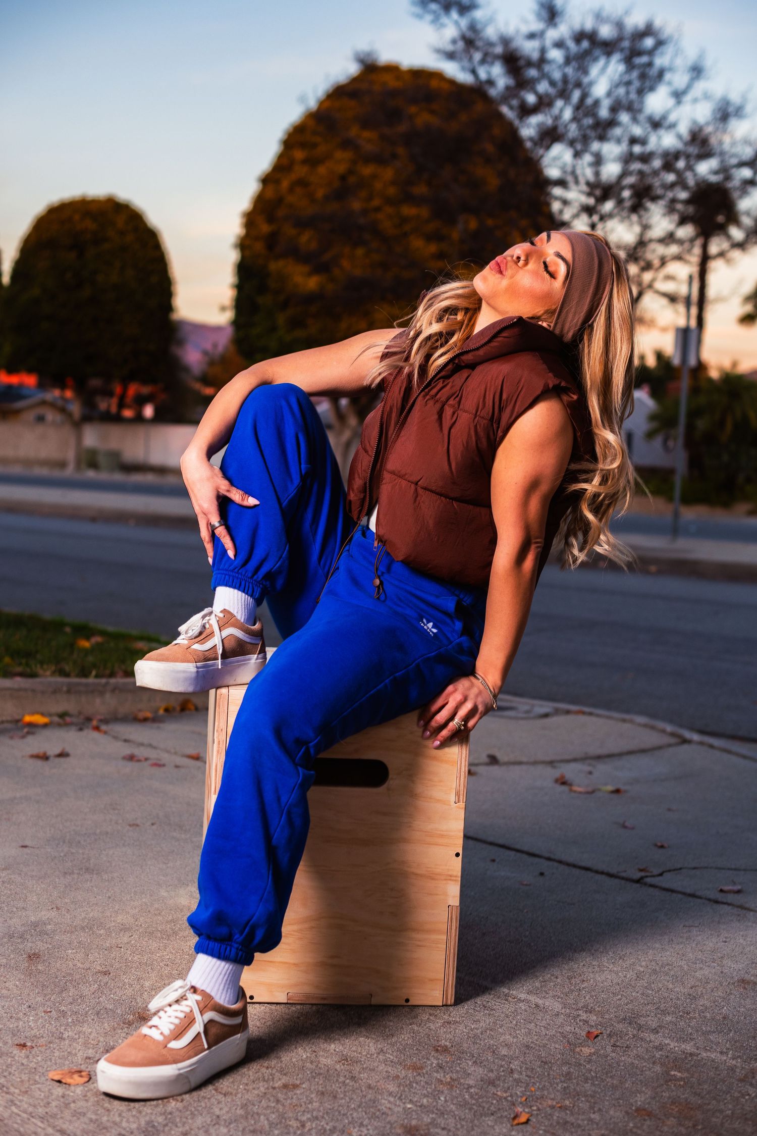 Relaxed pose on wooden box during golden hour wearing casual athletic wear.
