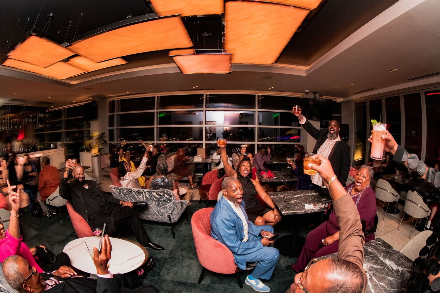 Panoramic view of wedding reception guests dancing and celebrating in an indoor venue.