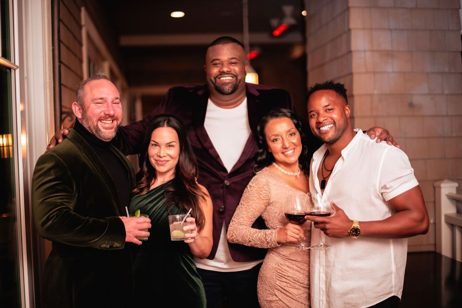 Diverse group of friends laughing and enjoying drinks together at a bar gathering.