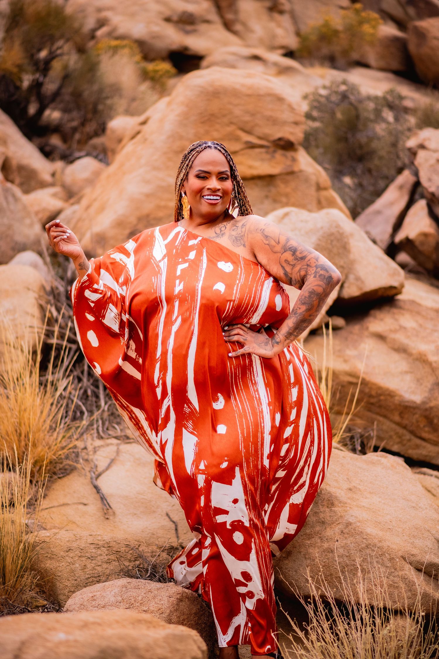 A flowing red polka dot dress billows against a desert rock backdrop in a fashion photoshoot.