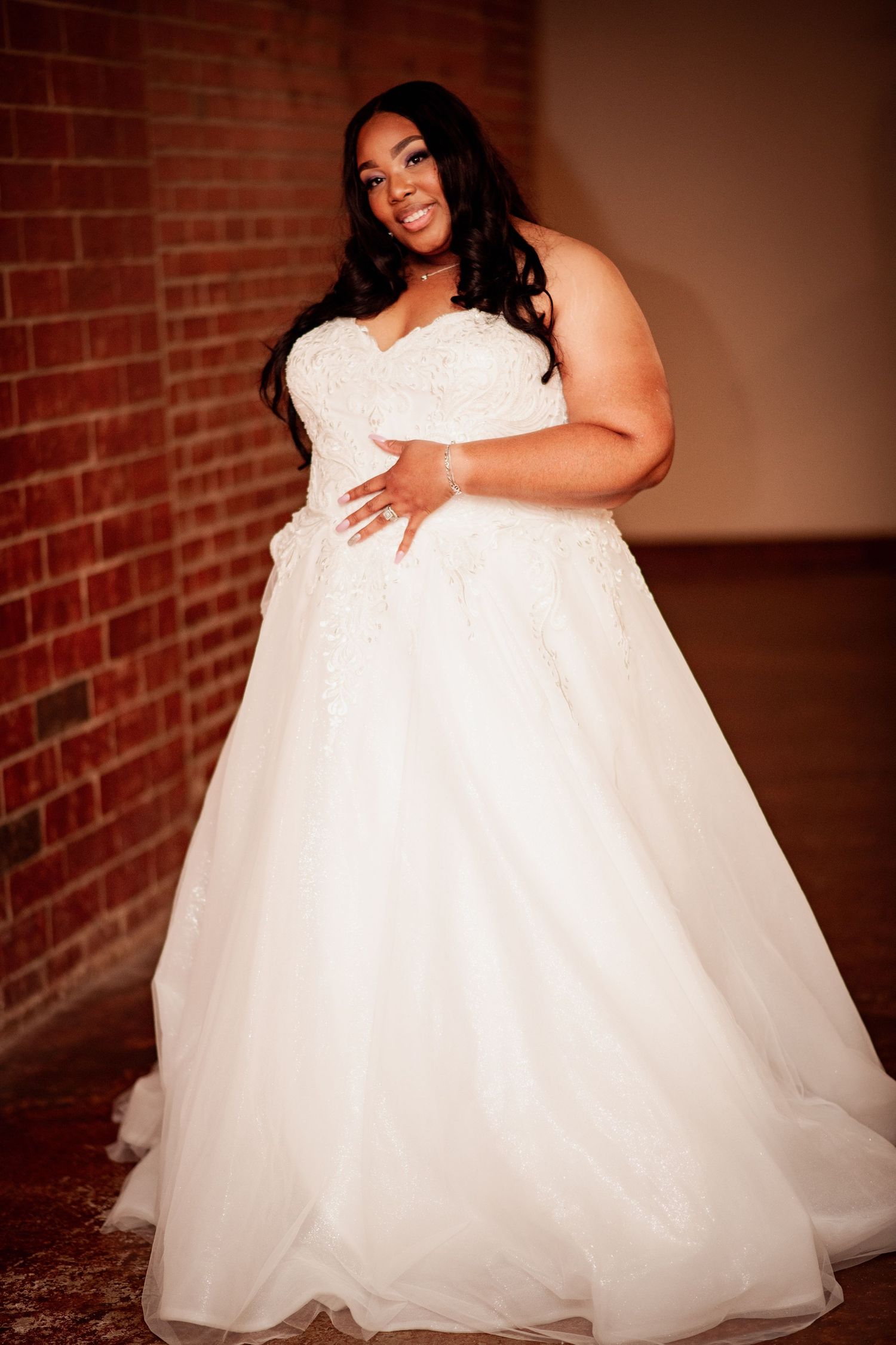 Flowing white wedding dress is shown in a series of detail shots against a brick wall background.