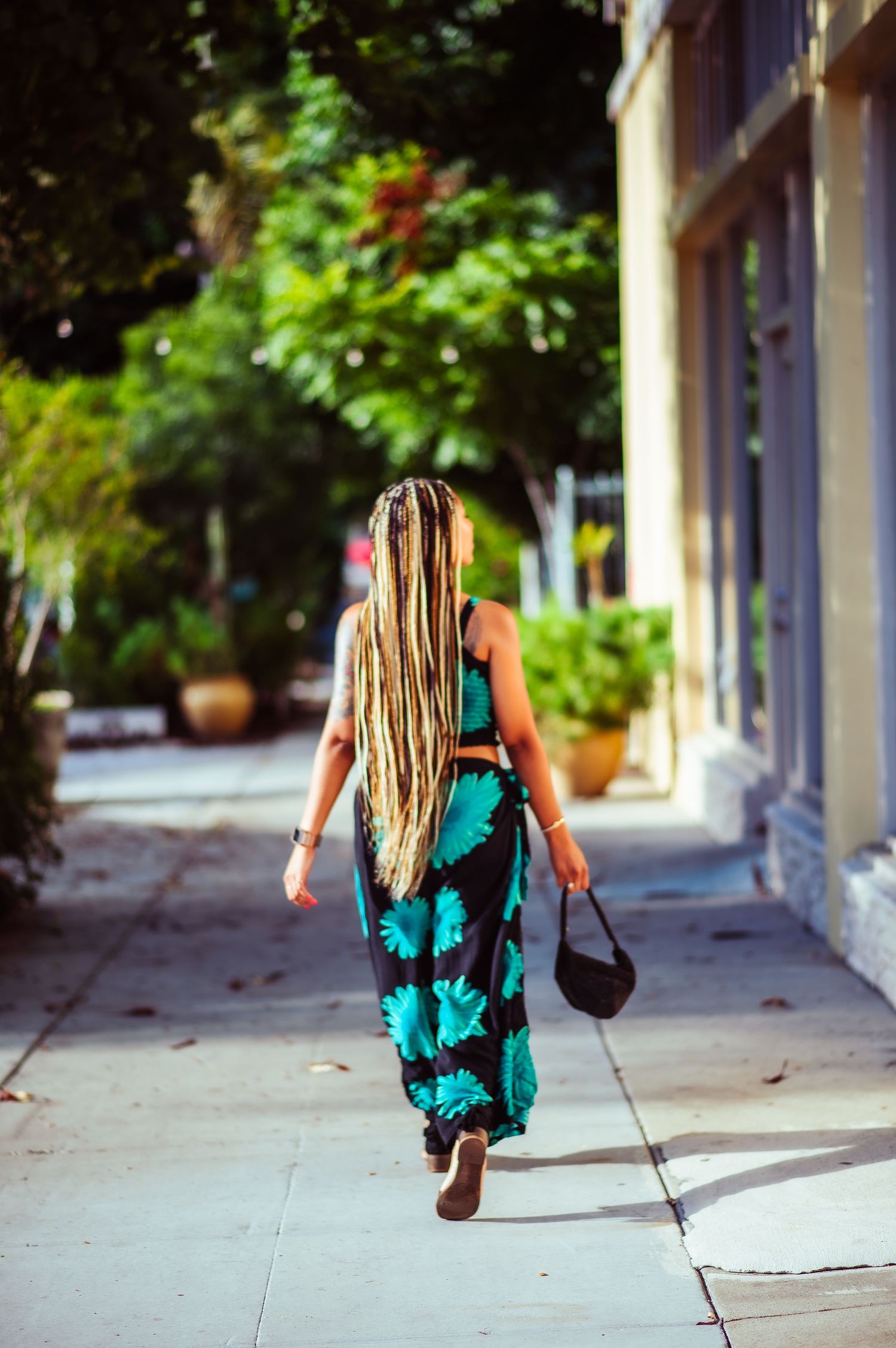 Dynamic walking shot showing movement in a turquoise and black summer dress.