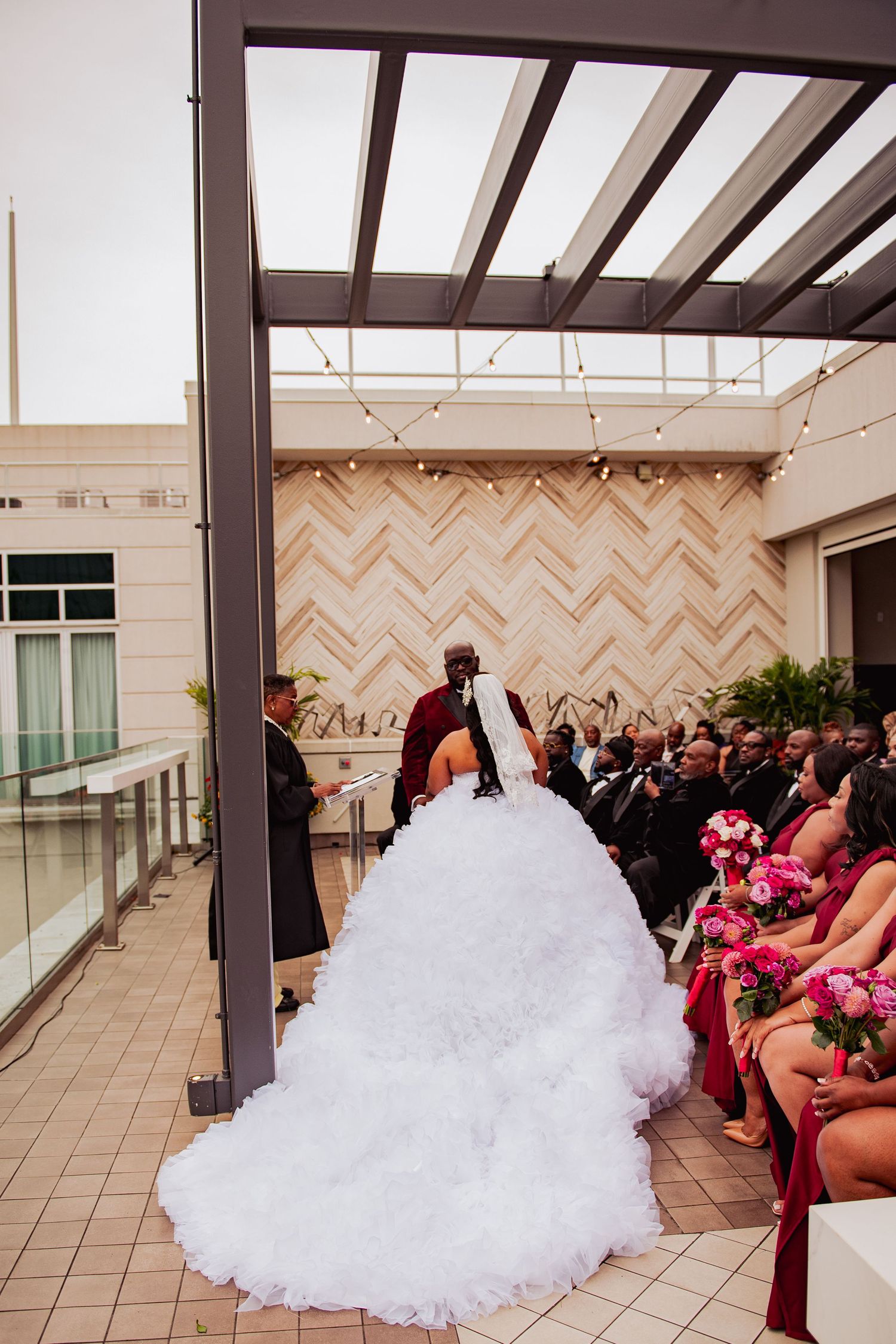 Modern rooftop wedding ceremony setup with geometric wall patterns and white chairs.