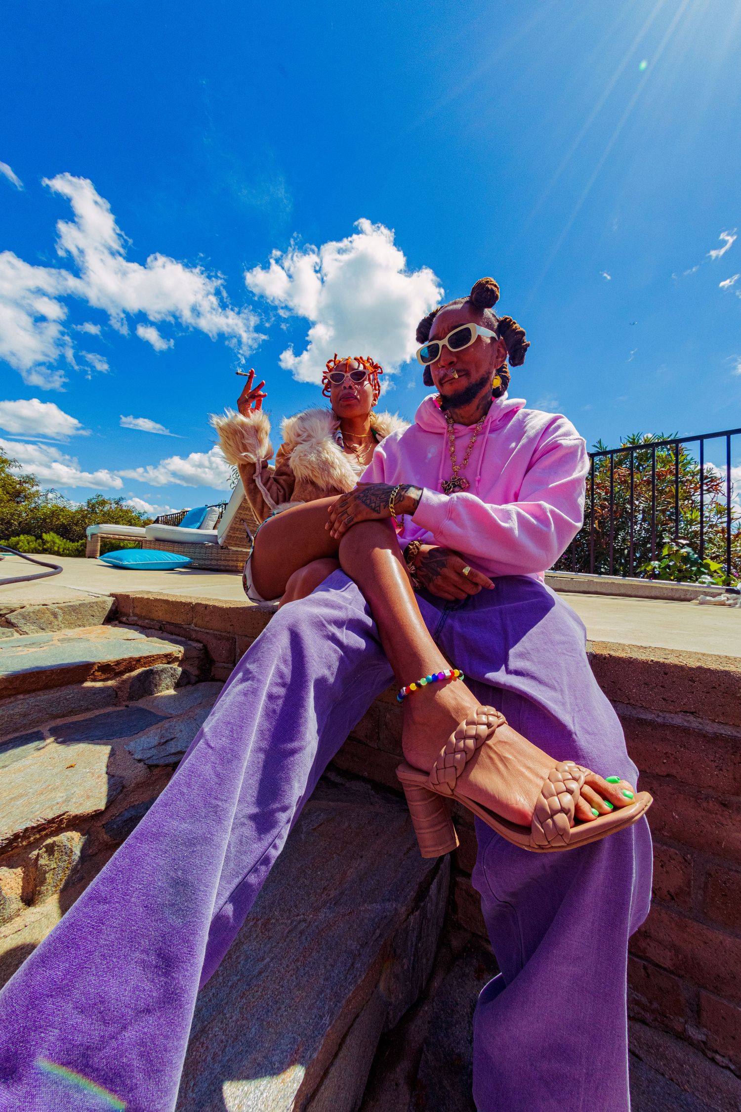Multiple synchronized shots capture a moment wearing vibrant purple outfits against a bright blue sky on a paved overlook.