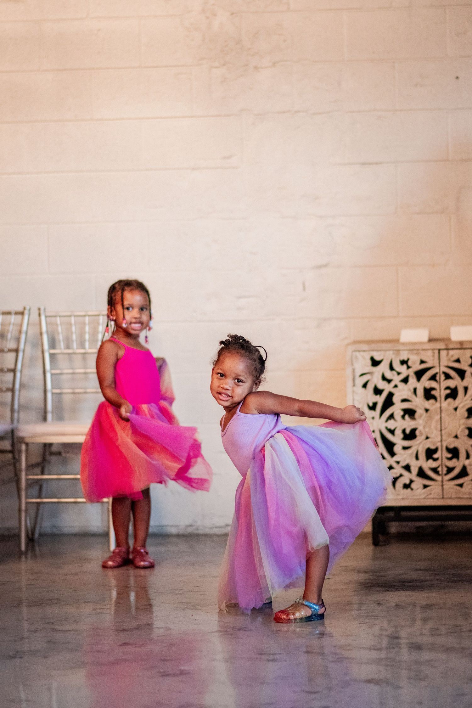 Young dancers in colorful tulle dresses twirling at a wedding reception.