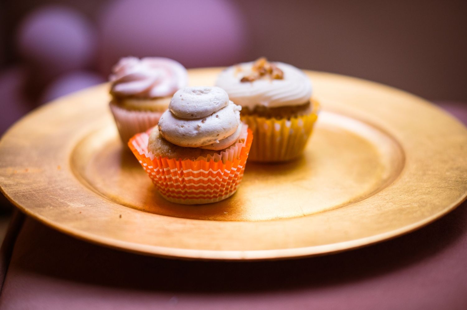 Cupcakes with white frosting displayed on golden plates with warm ambient lighting.