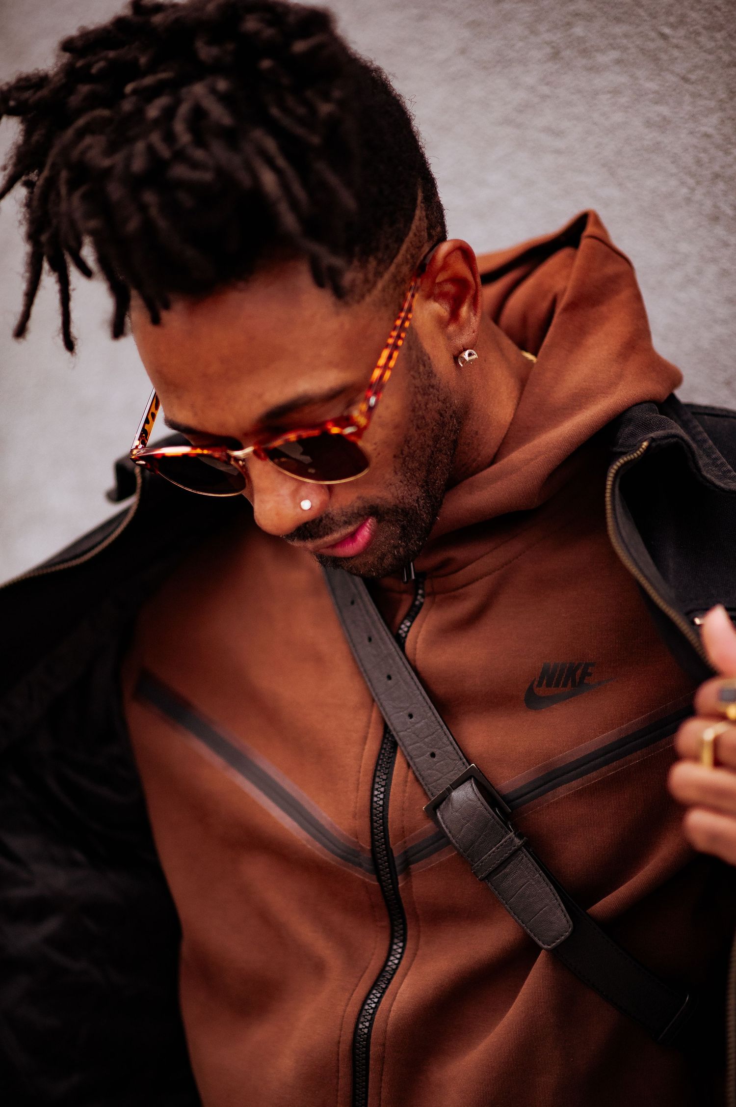 A sequence of close-up shots showing a brown leather bag with black zipper details and adjustable straps.