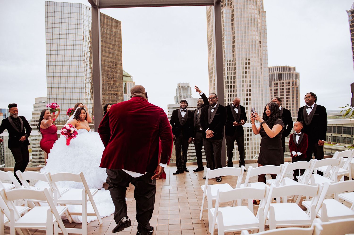 Outdoor rooftop wedding ceremony setup with city skyline backdrop and white chairs.