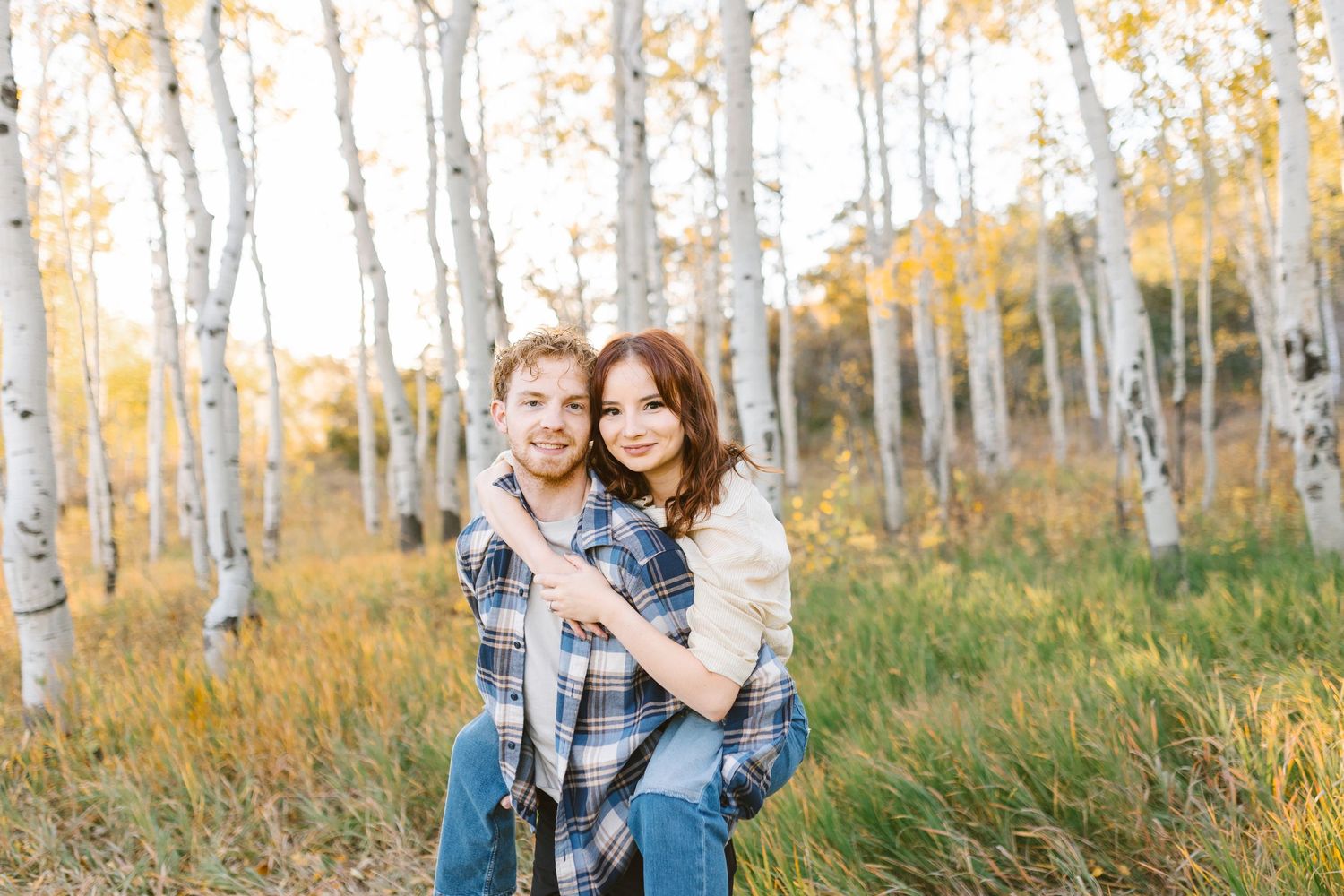 Series of candid moments between couple in autumn birch forest.