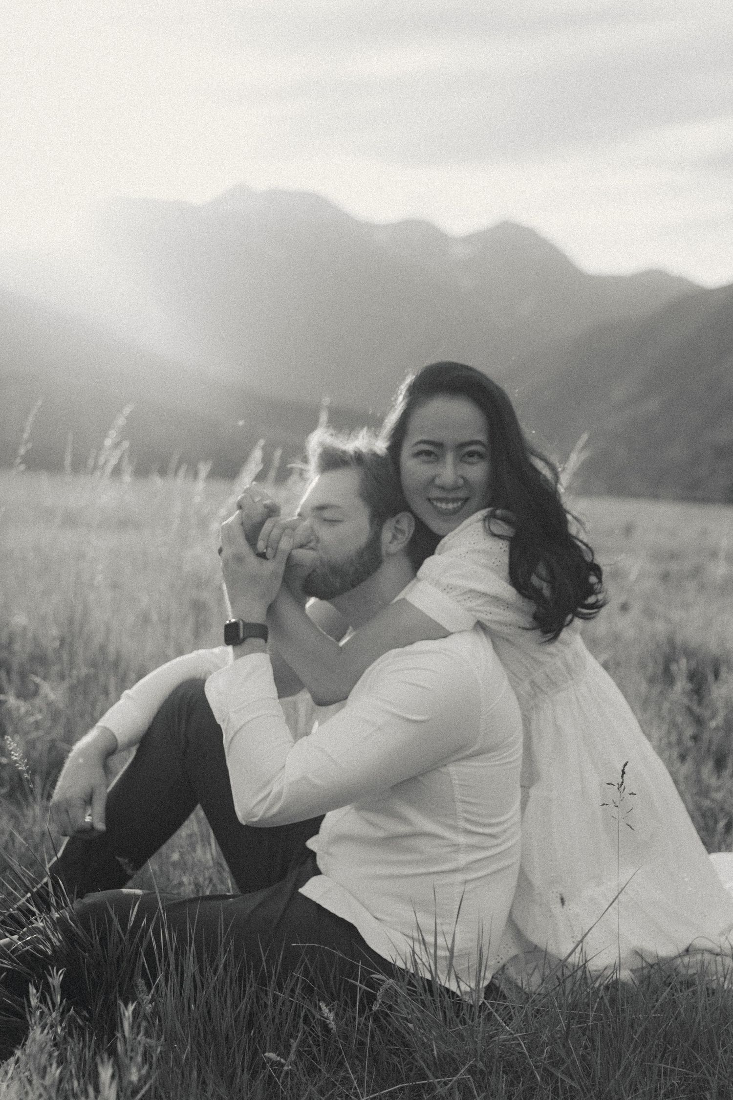 Black and white portrait of couple relaxing in mountain meadow.