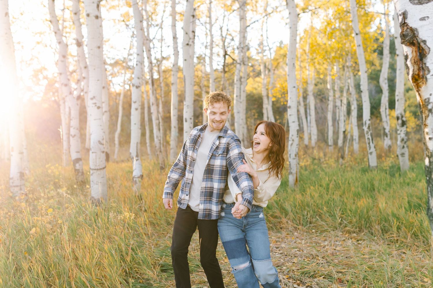 Romantic autumn engagement photos in sunlit aspen forest.