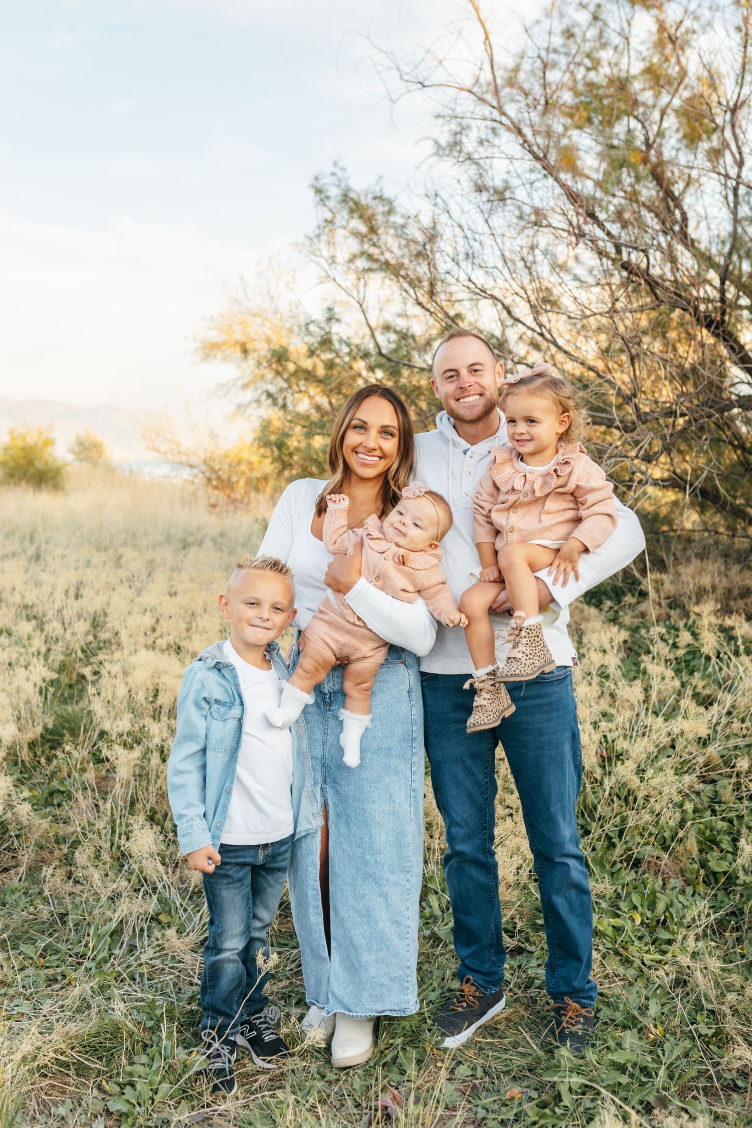 A candid family photo session in a sunlit field with natural golden lighting.