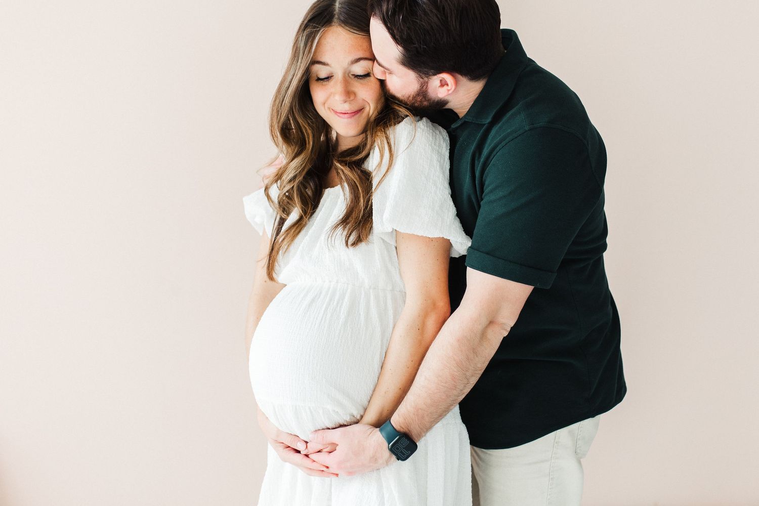 Intimate maternity portrait of couple in white dress and black shirt.