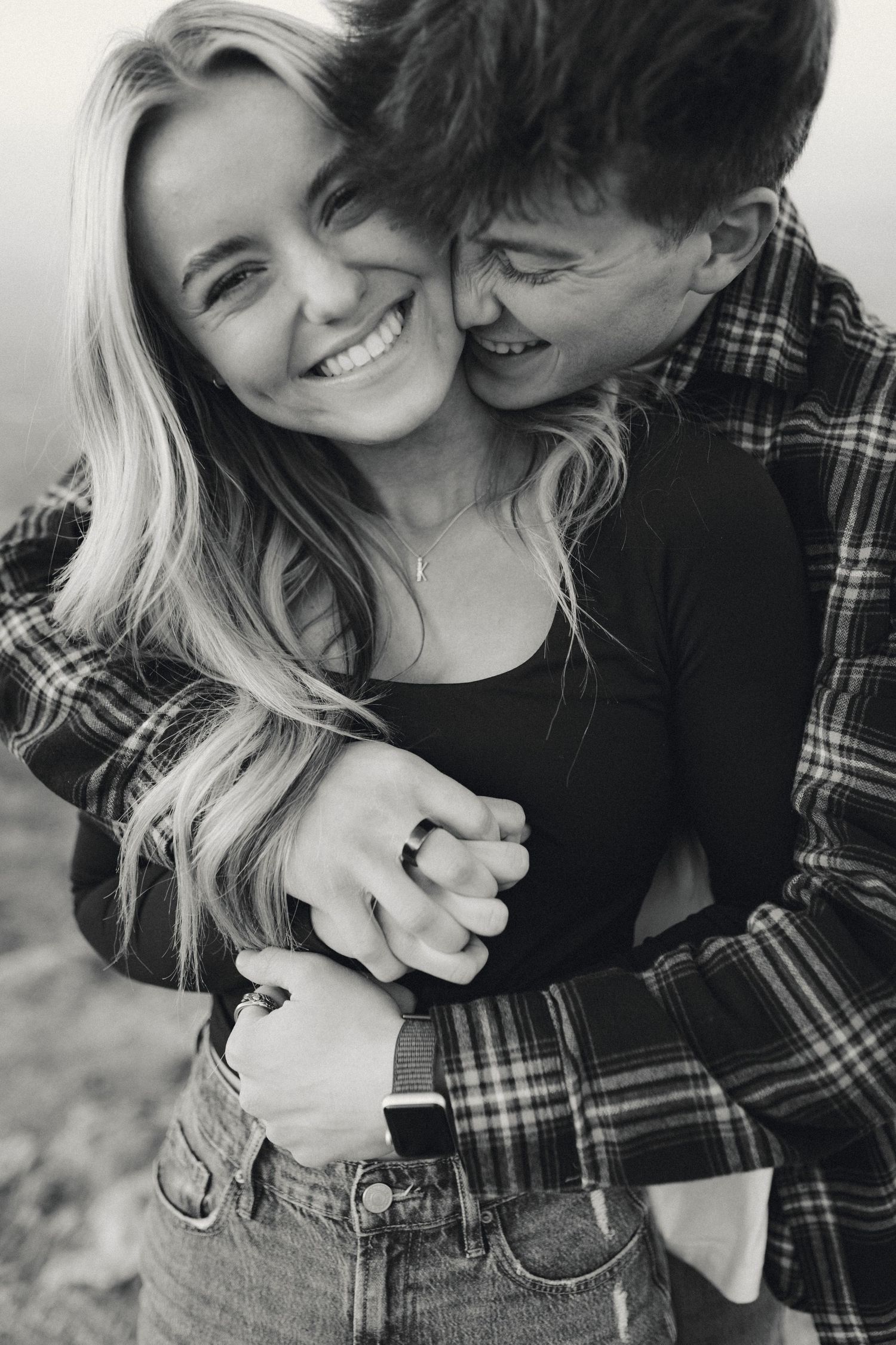 A romantic black and white portrait of a couple embracing and laughing together.