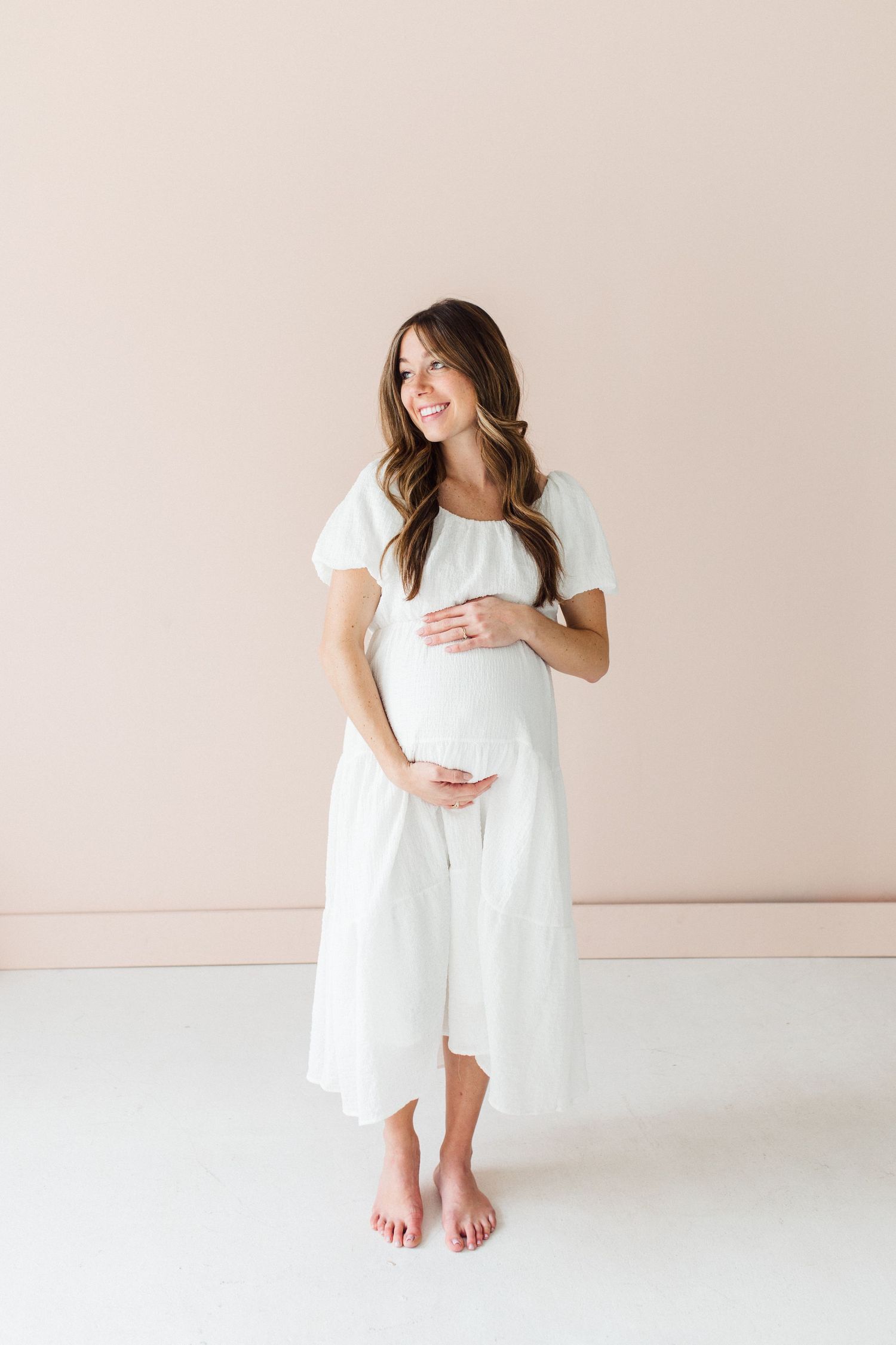 Full-length maternity photos in white dress against neutral background showing different poses.