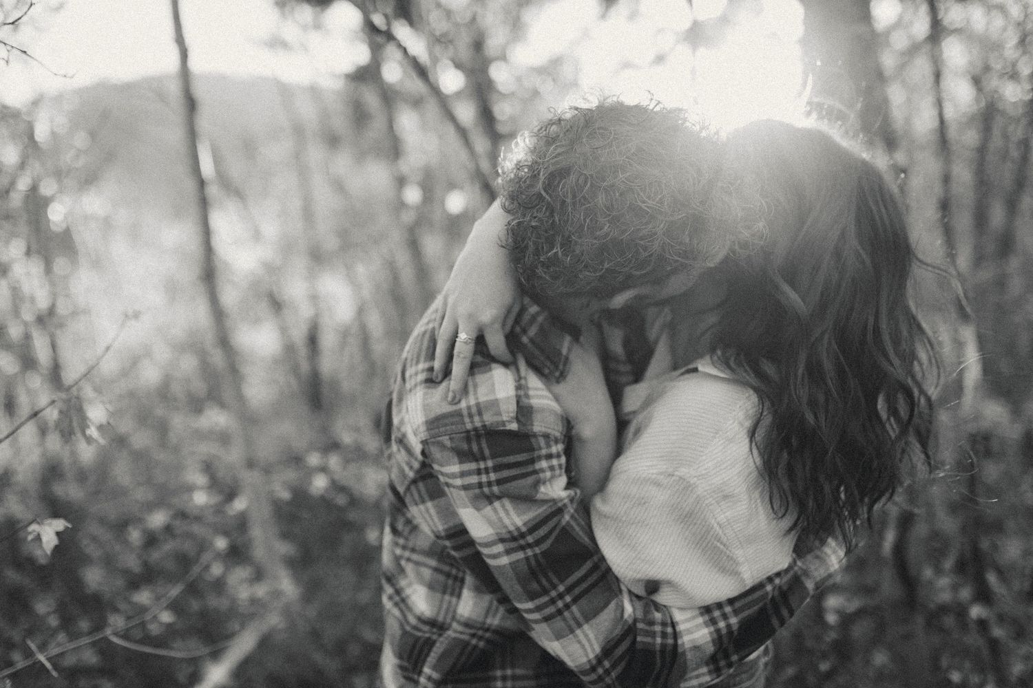Silhouetted couple shares tender moment in sunlit aspen grove.