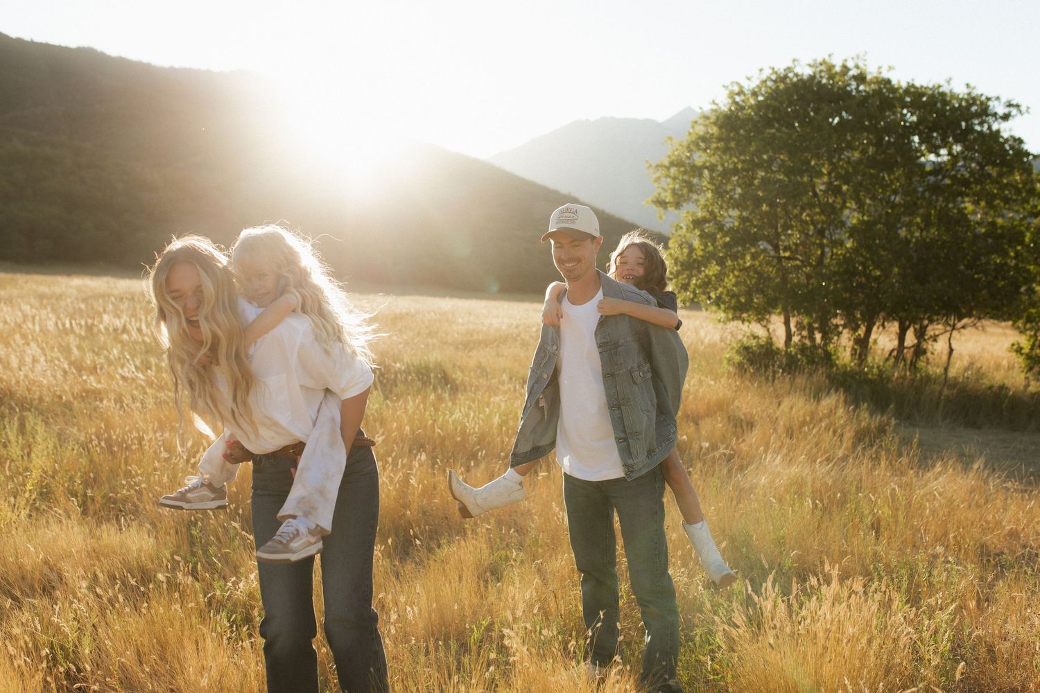 Romantic couple embraces in golden sunlit meadow during sunset photoshoot session.