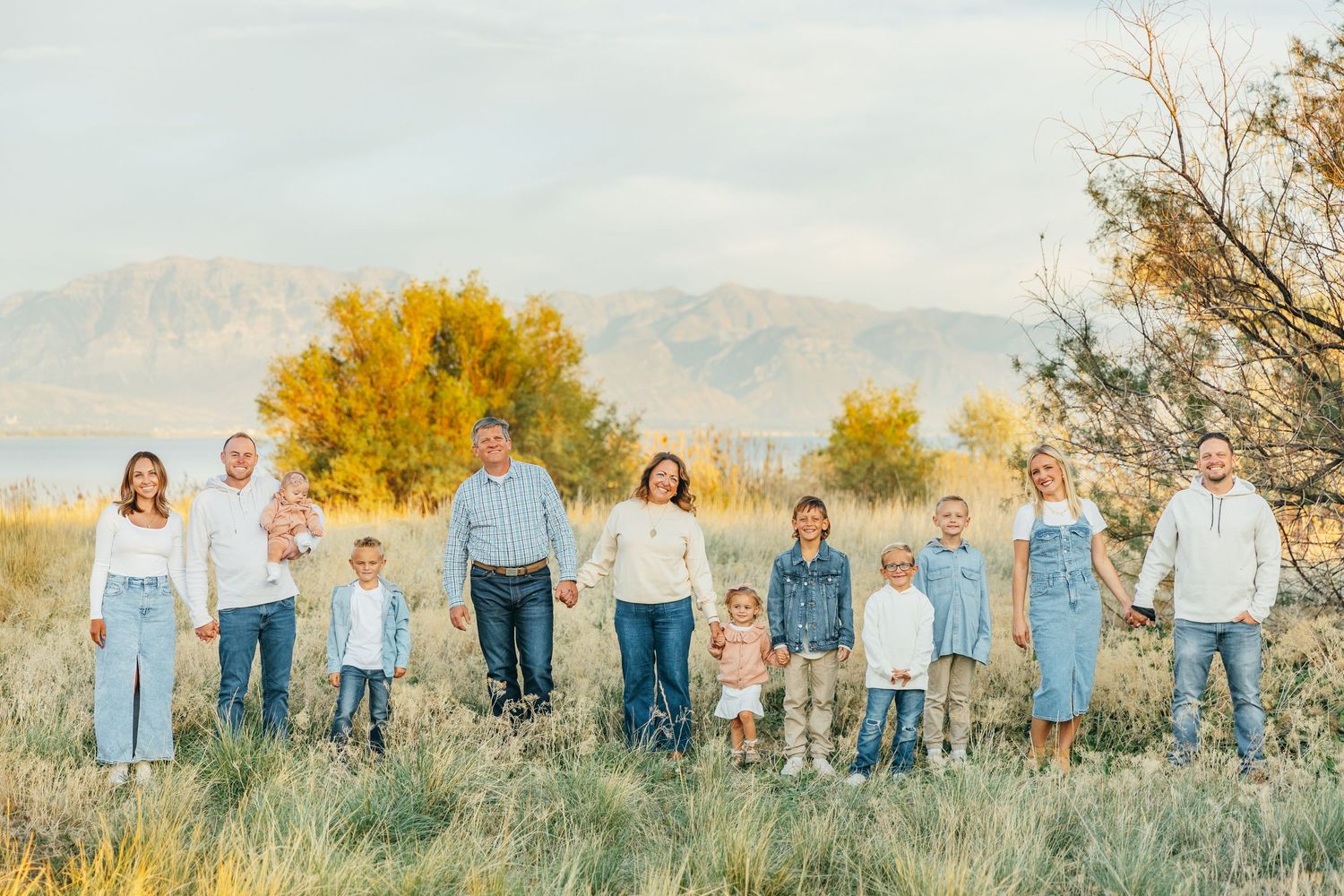 Large family group portrait in matching blue and white outfits against mountain backdrop.
