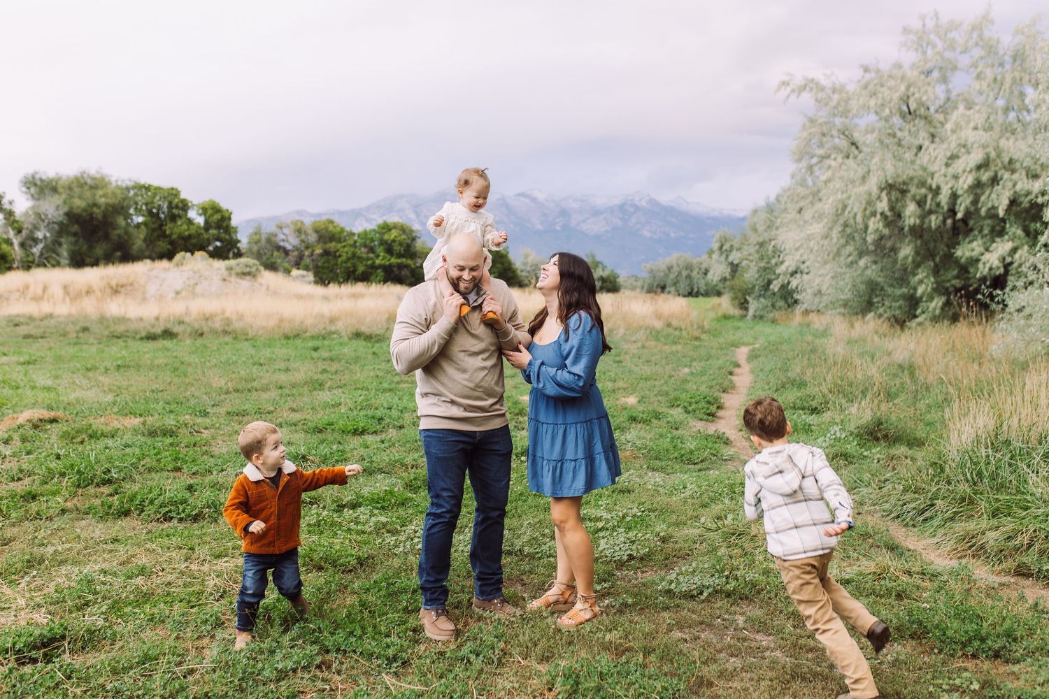 A family enjoys a playful moment together in a scenic mountain meadow.